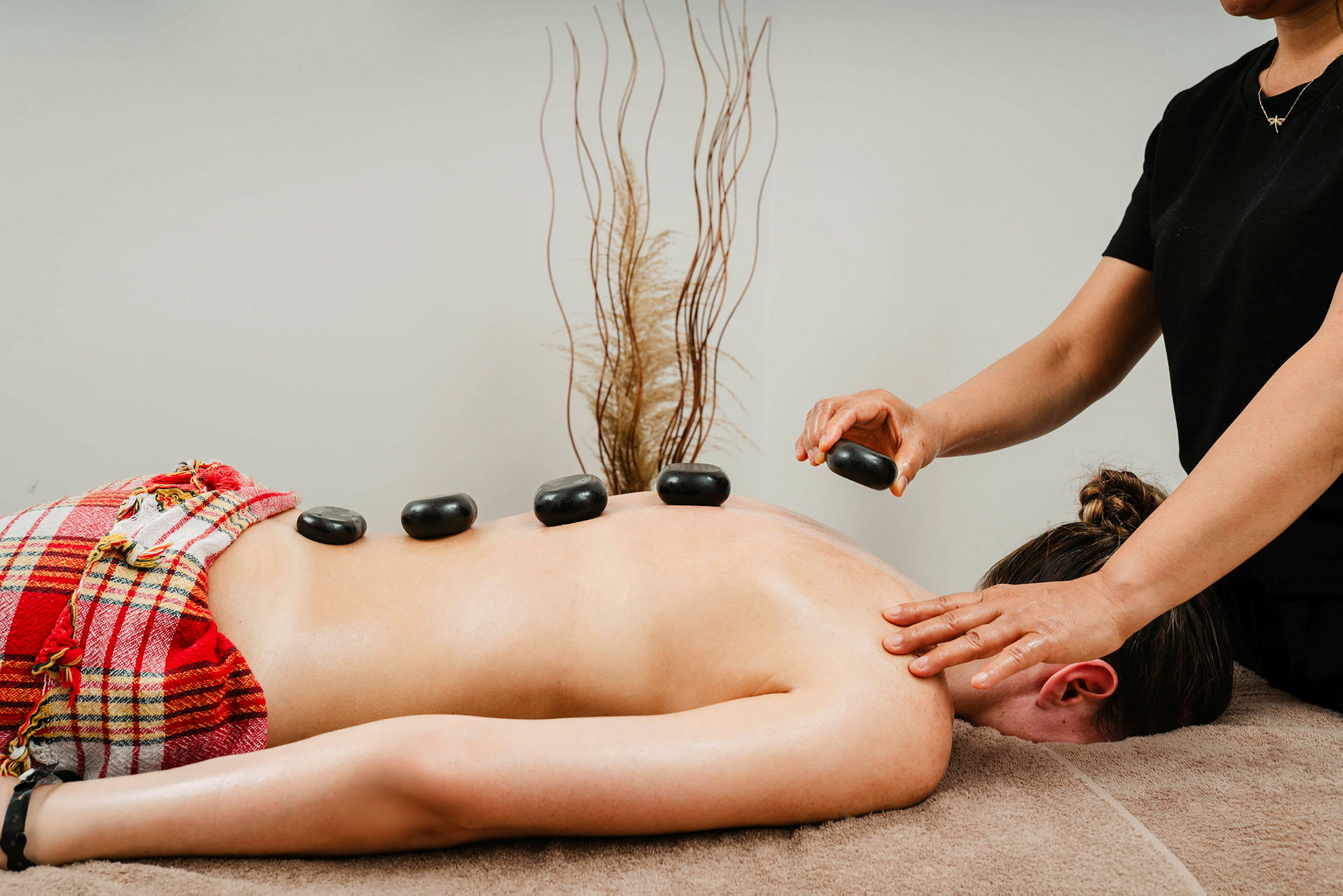 En person får hot stone-massage med sten placeret på ryggen. (AI-genereret tekst)
