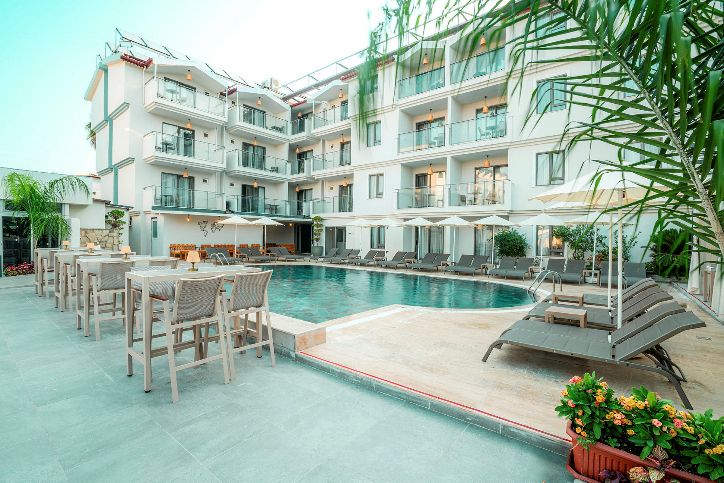 Billede af hotel med flere etager og en pool omgivet af liggestole og borde. (AI-genereret tekst)