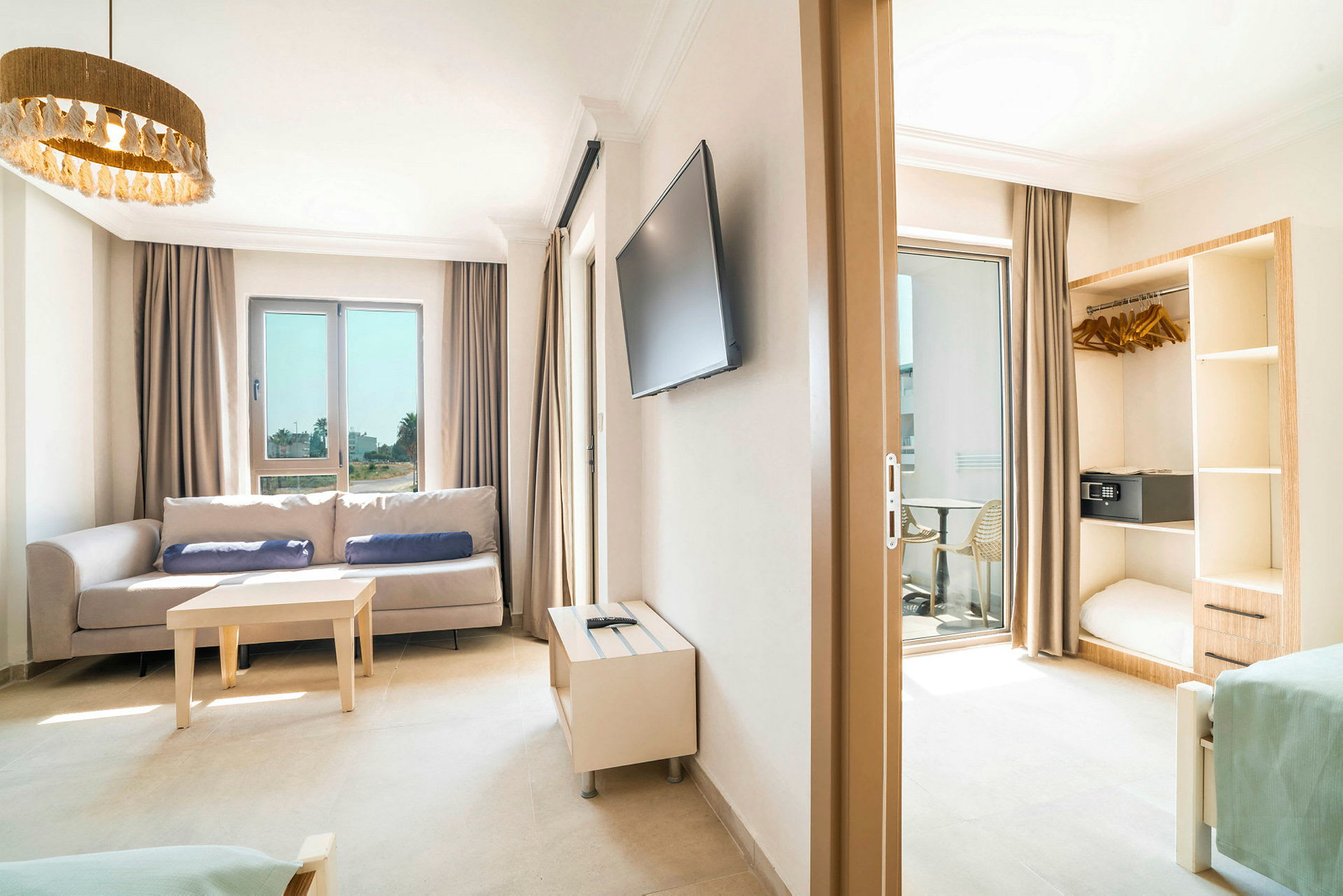 Billede af et lyst hotelværelse med sofa, bord, TV og åben garderobe. (AI-genereret tekst)
