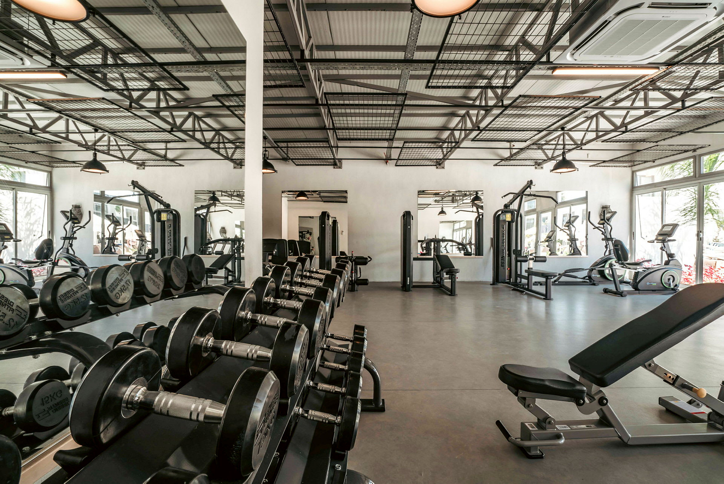 Træningscenter med fitnessmaskiner, håndvægte og spejle. (AI-genereret tekst)
