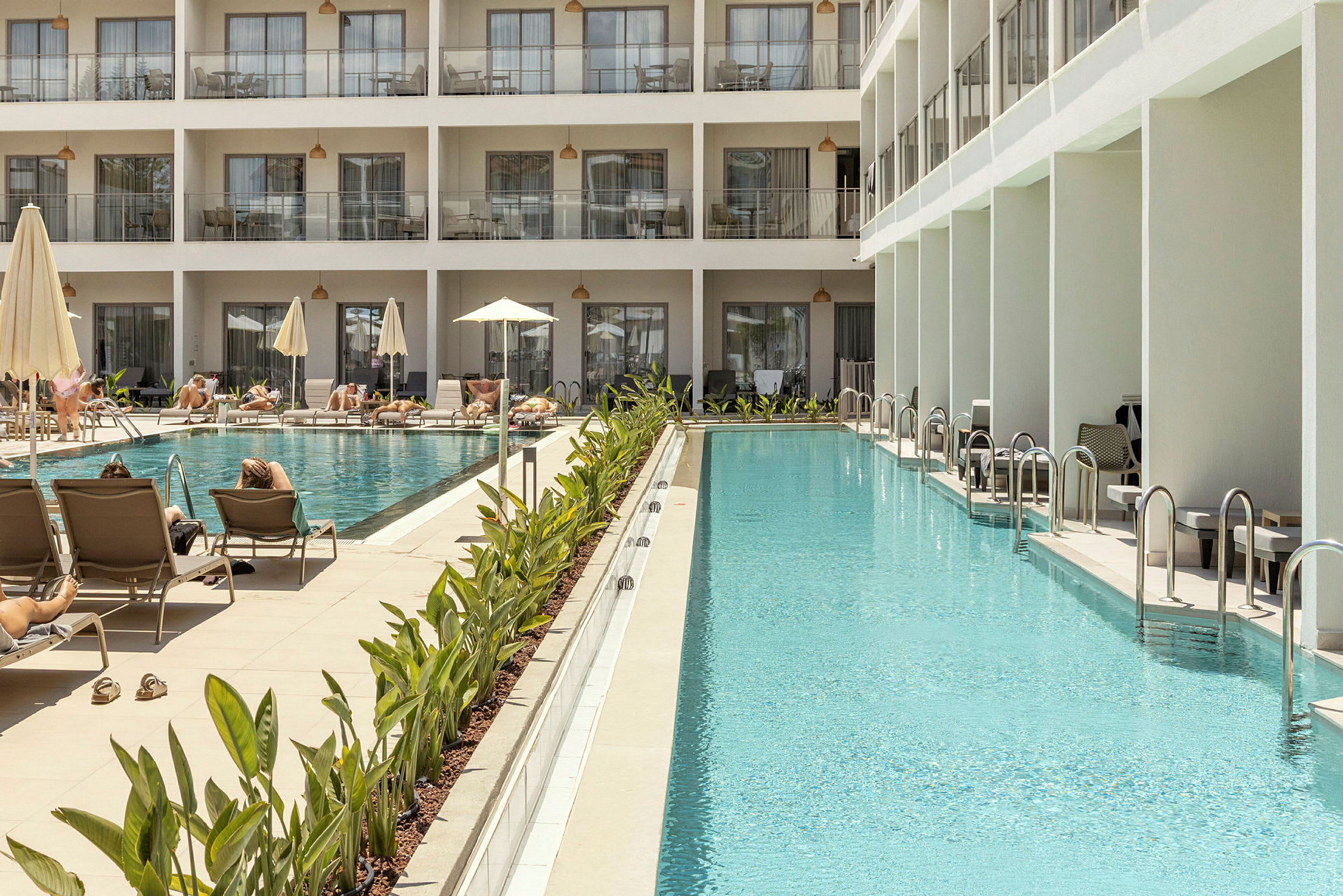 Et luksuriøst hotel med liggestole og parasoller ved en stor pool. (AI-genereret tekst)