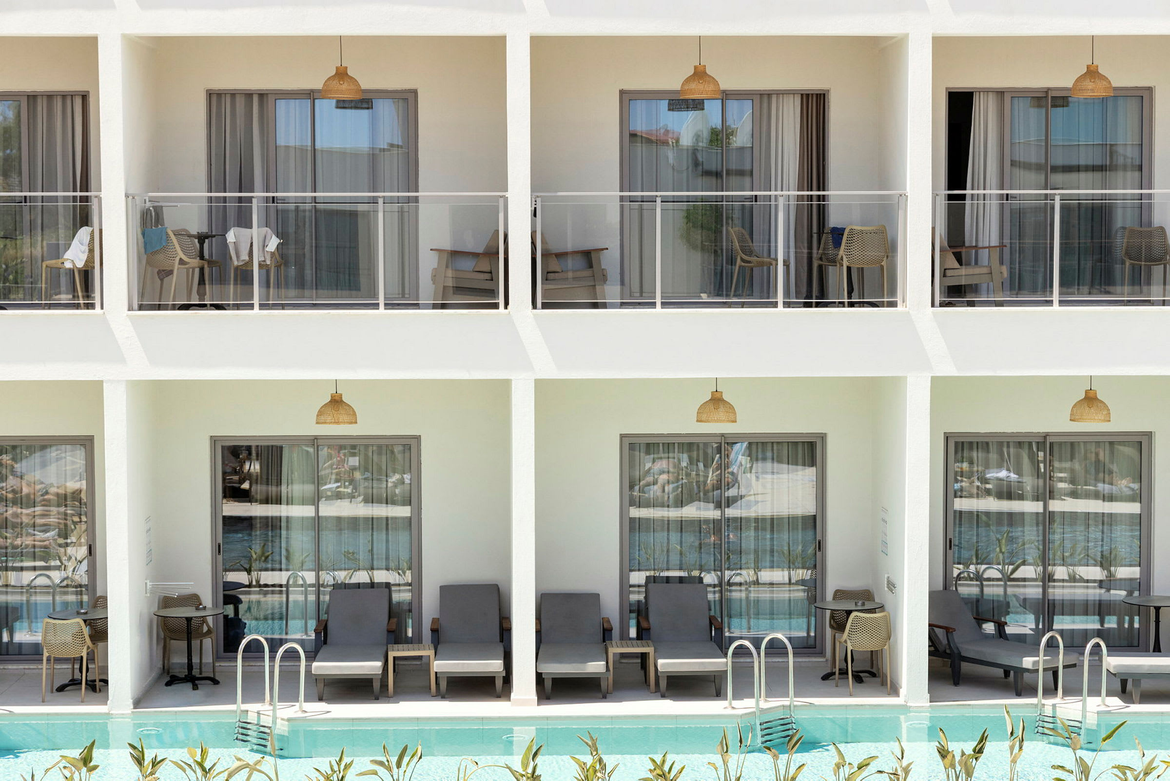 Billede af en moderne hotelfacade med altaner og direkte forbindelse til en udendørs pool. (AI-genereret tekst)
