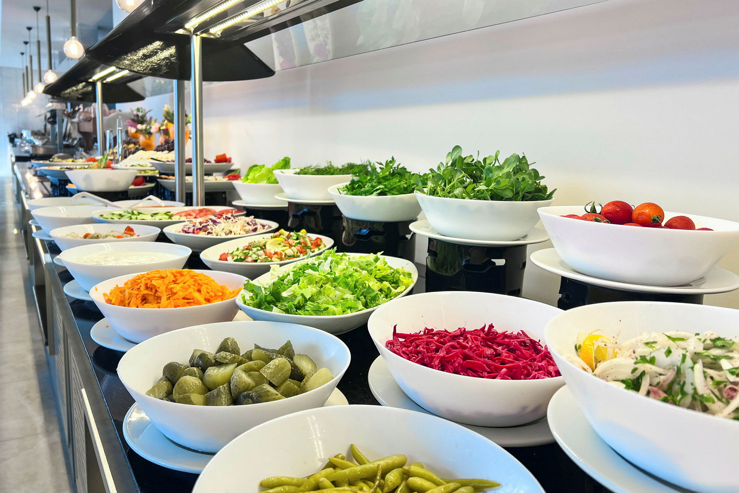 En buffet med salat og grøntsager i hvide skåle. (AI-genereret tekst)