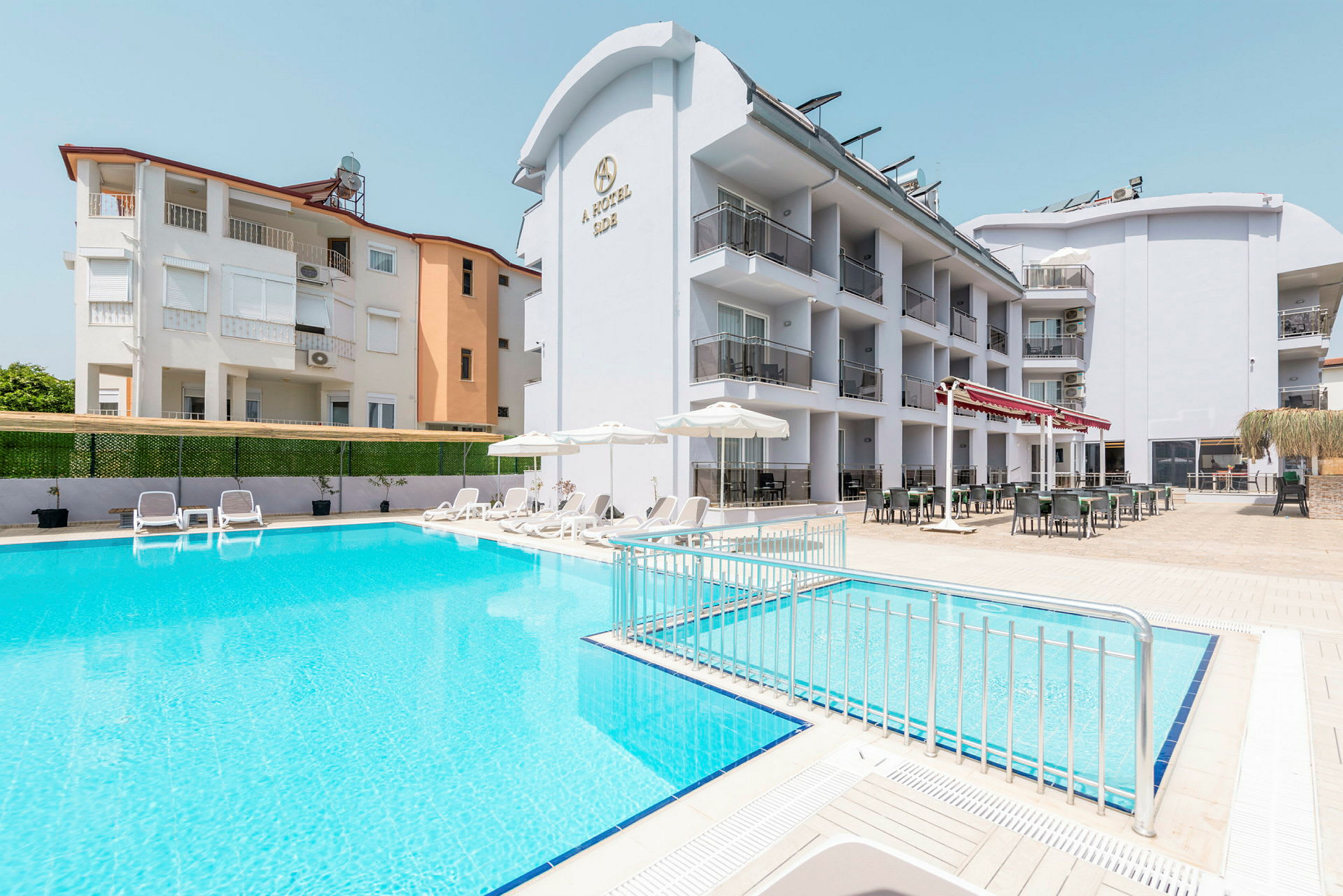 Hotel med poolområde og liggestole i forgrunden. (AI-genereret tekst)