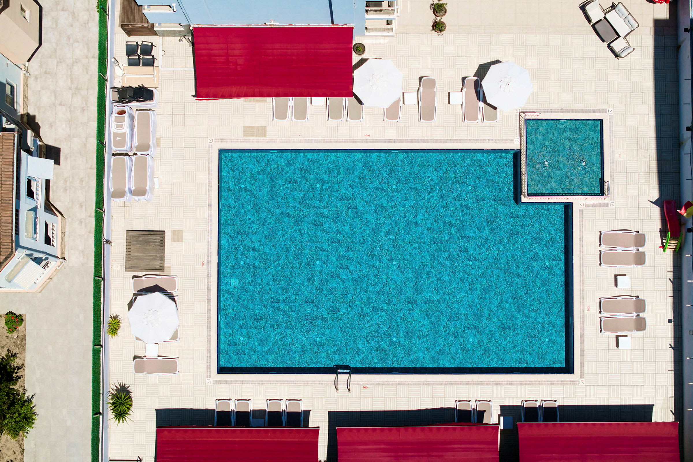 Luftfoto af en swimmingpool og liggestole på et poolområde. (AI-genereret tekst)