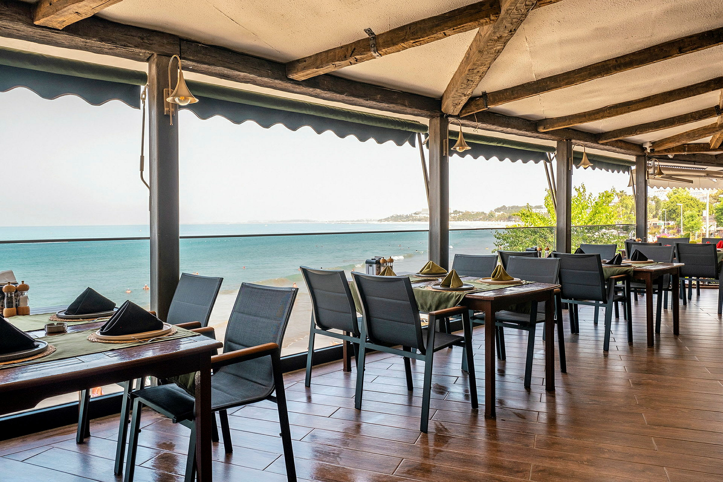 Restaurantborde med borddækning og udsigt over havet. (AI-genereret tekst)