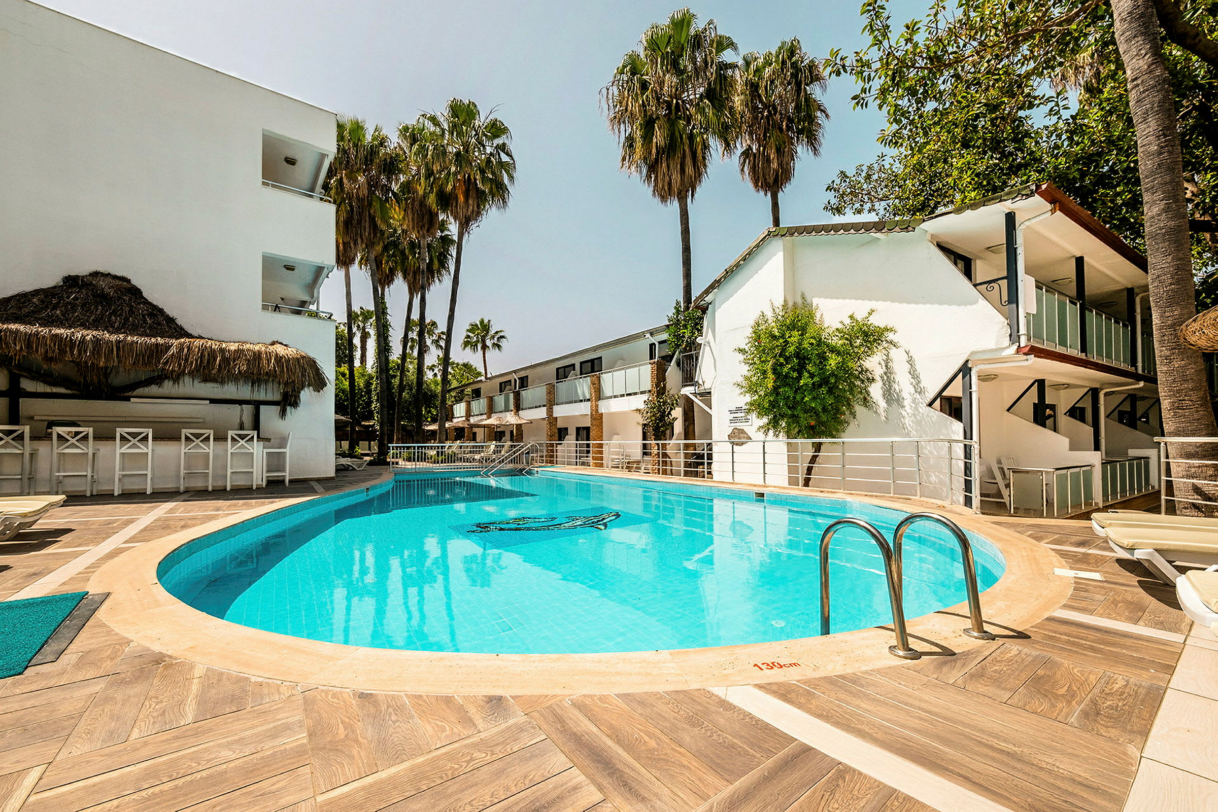 Udendørs pool ved hotel med liggestole og palmer. (AI-genereret tekst)