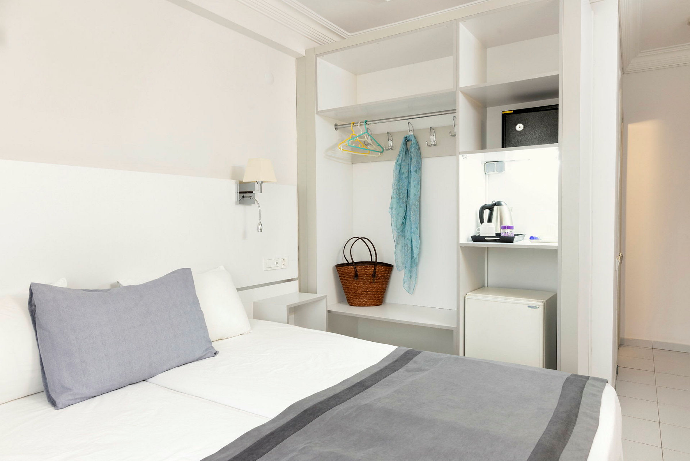 Hotelværelse med seng, garderobe og en minikøleskab. (AI-genereret tekst)