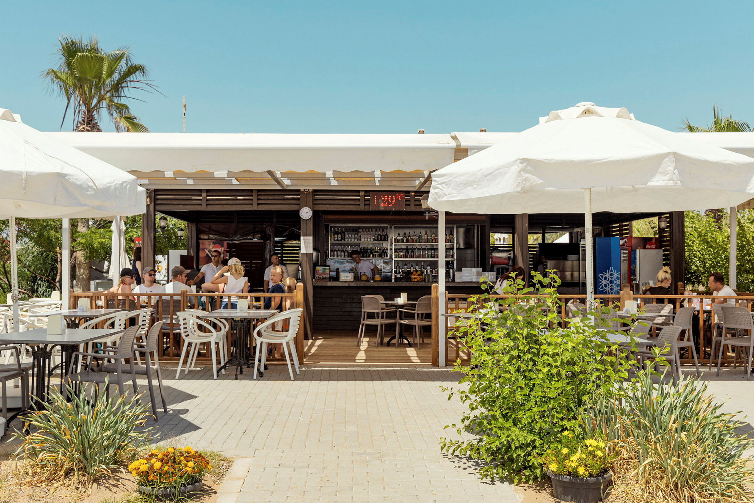 Udendørsrestaurant med parasoller og siddegrupper på terrasse. (AI-genereret tekst)