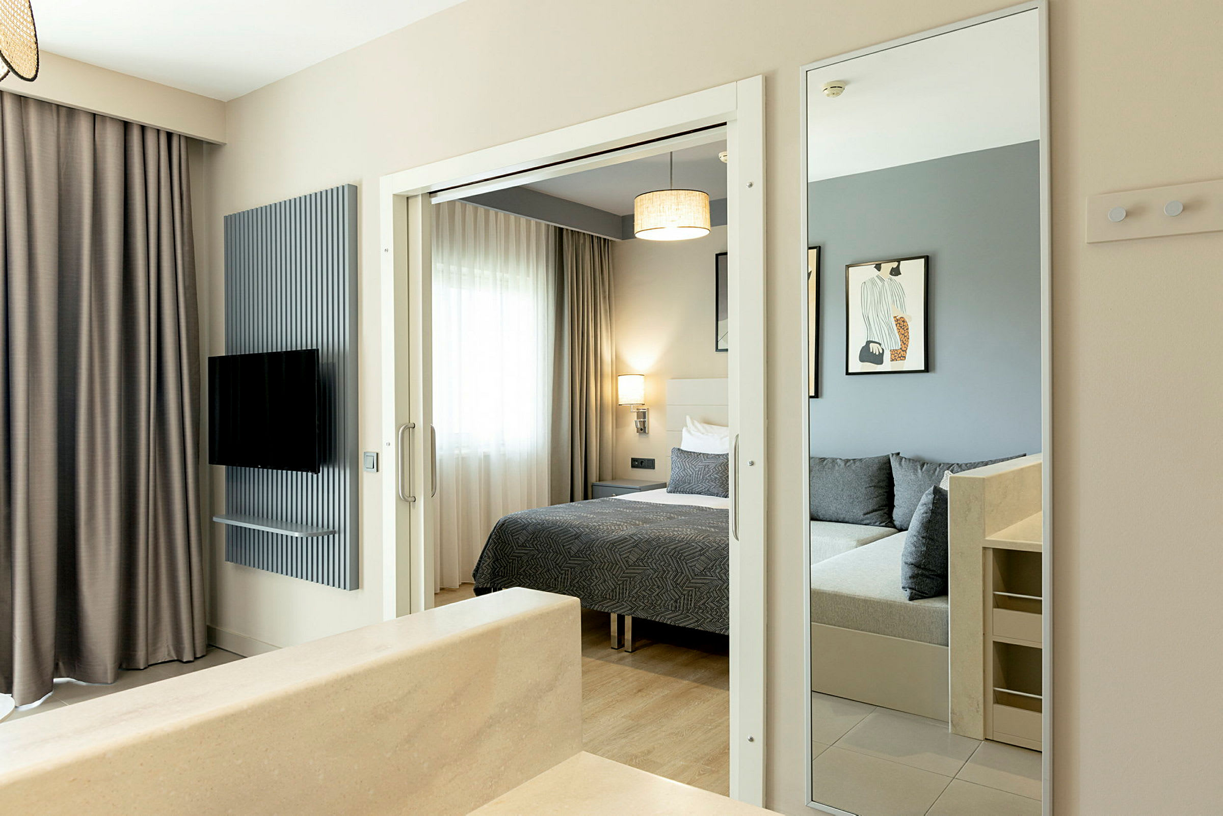 Billede af et hotelværelse med seng, spejl og tv. (AI-genereret tekst)