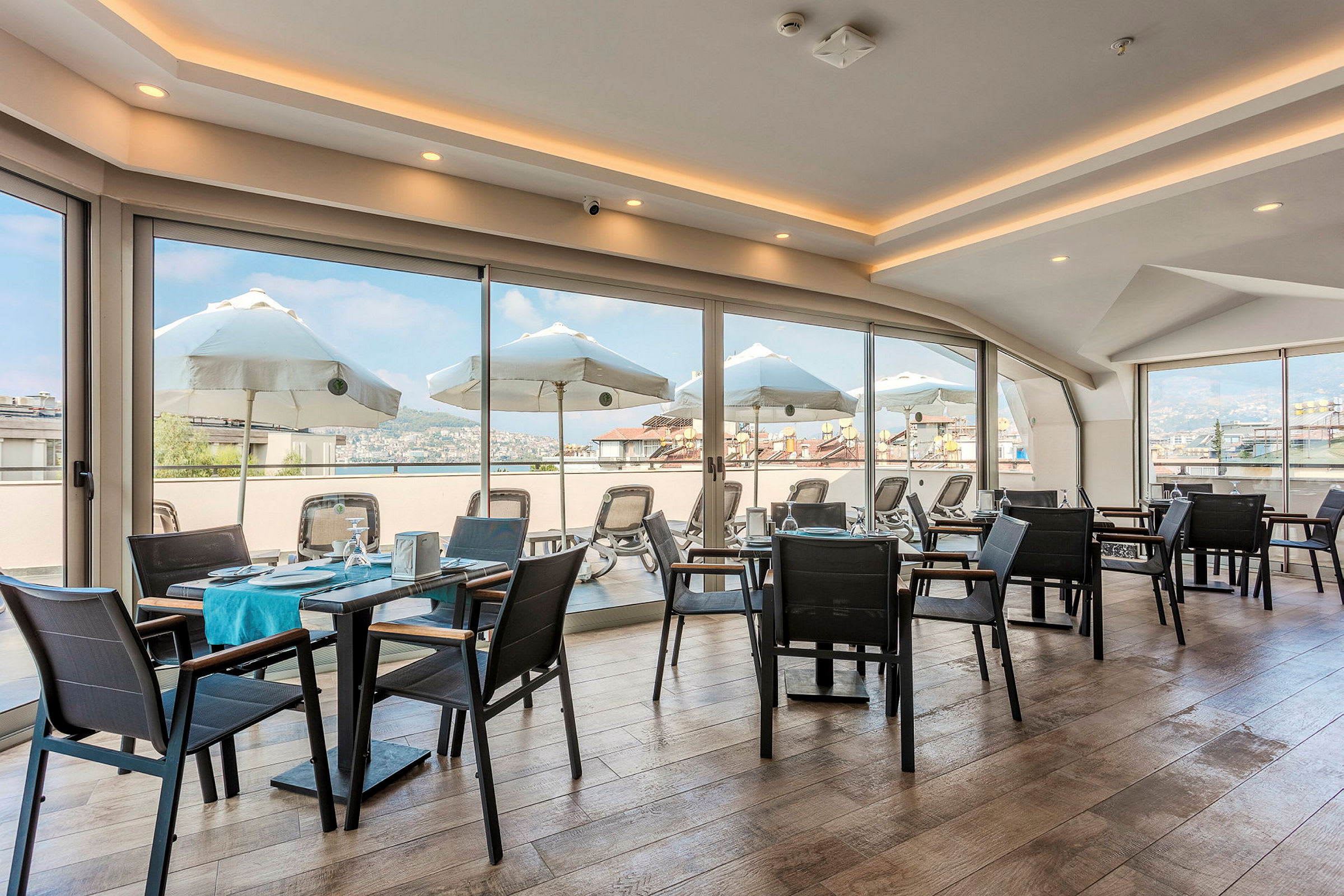 En restaurant med glasvægge og udsigt til parasoller og omgivelser. (AI-genereret tekst)