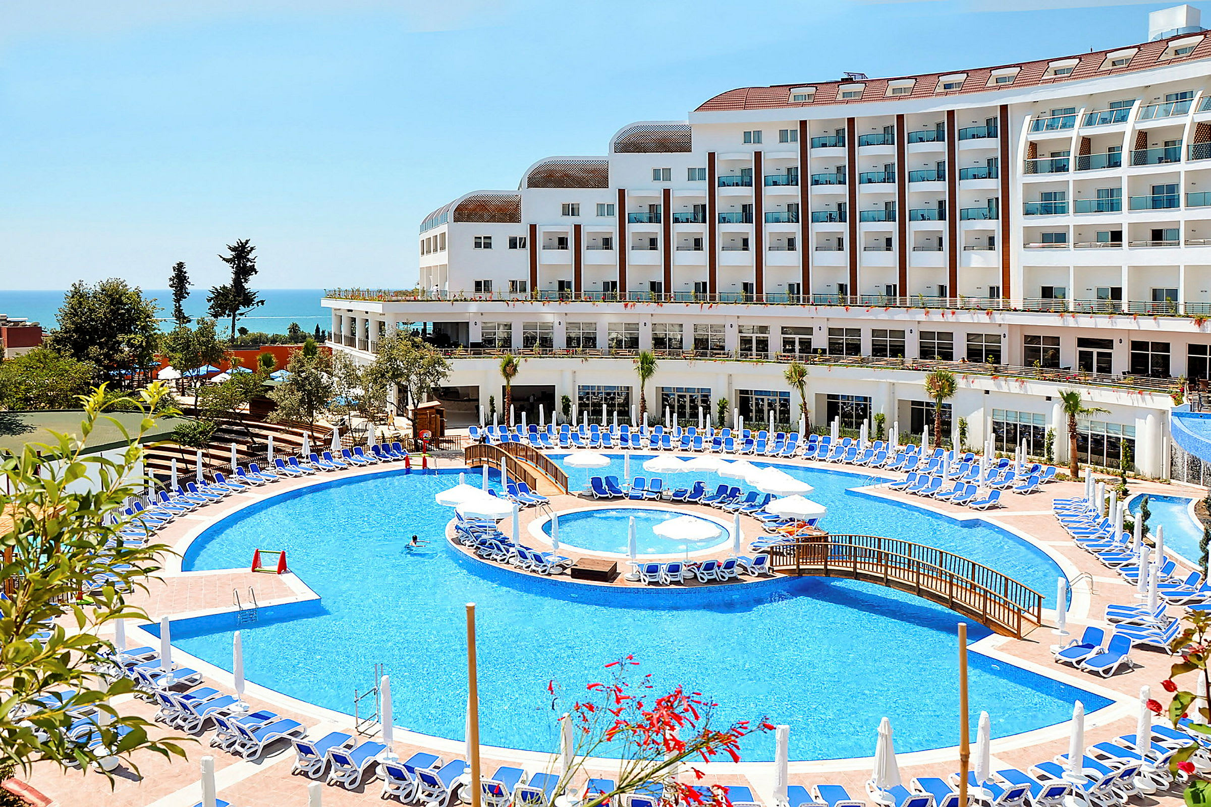 Hotel med stor pool og liggestole ved havet. (AI-genereret tekst)