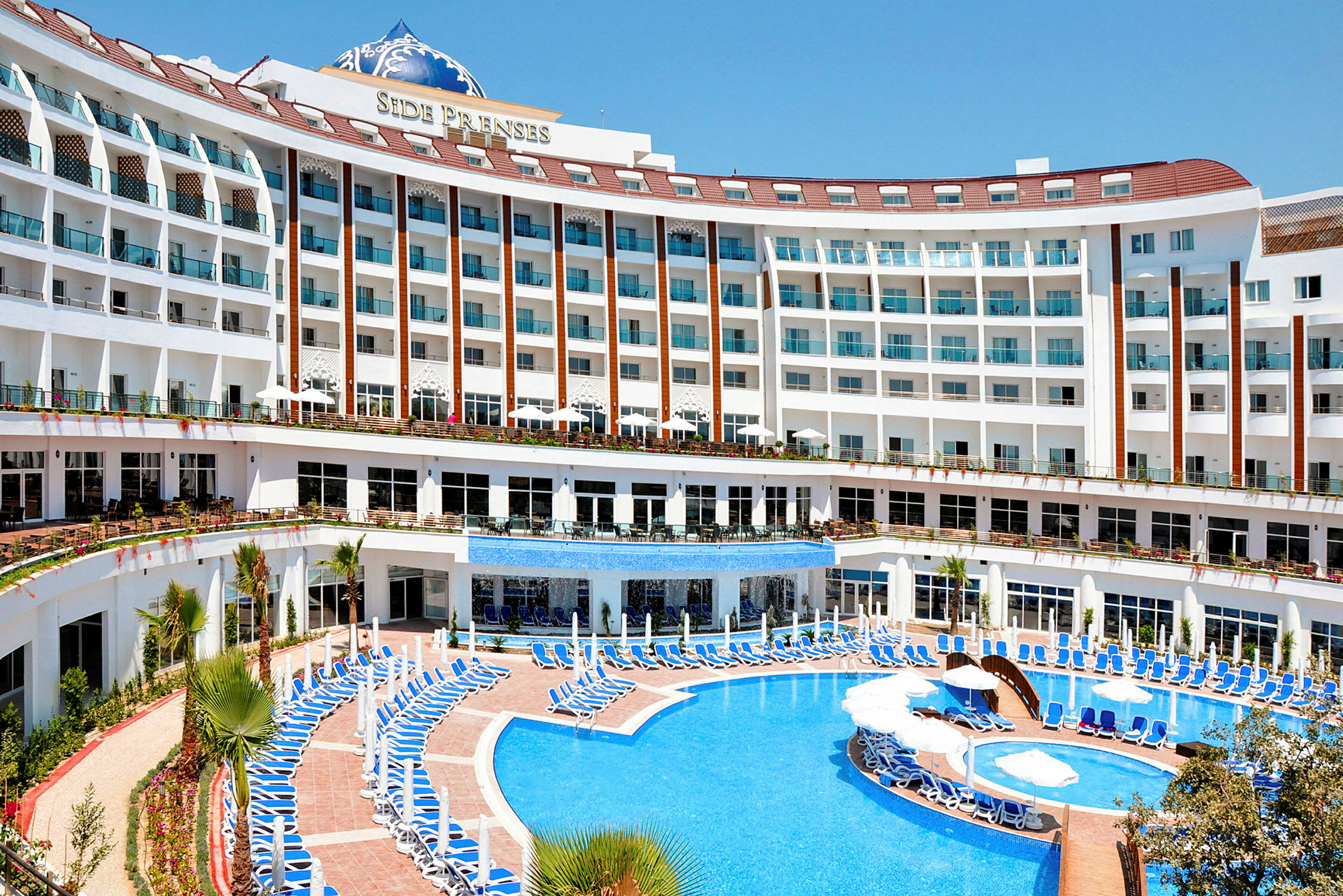 Et hotel med flere etager og en stor udendørs pool. (AI-genereret tekst)
