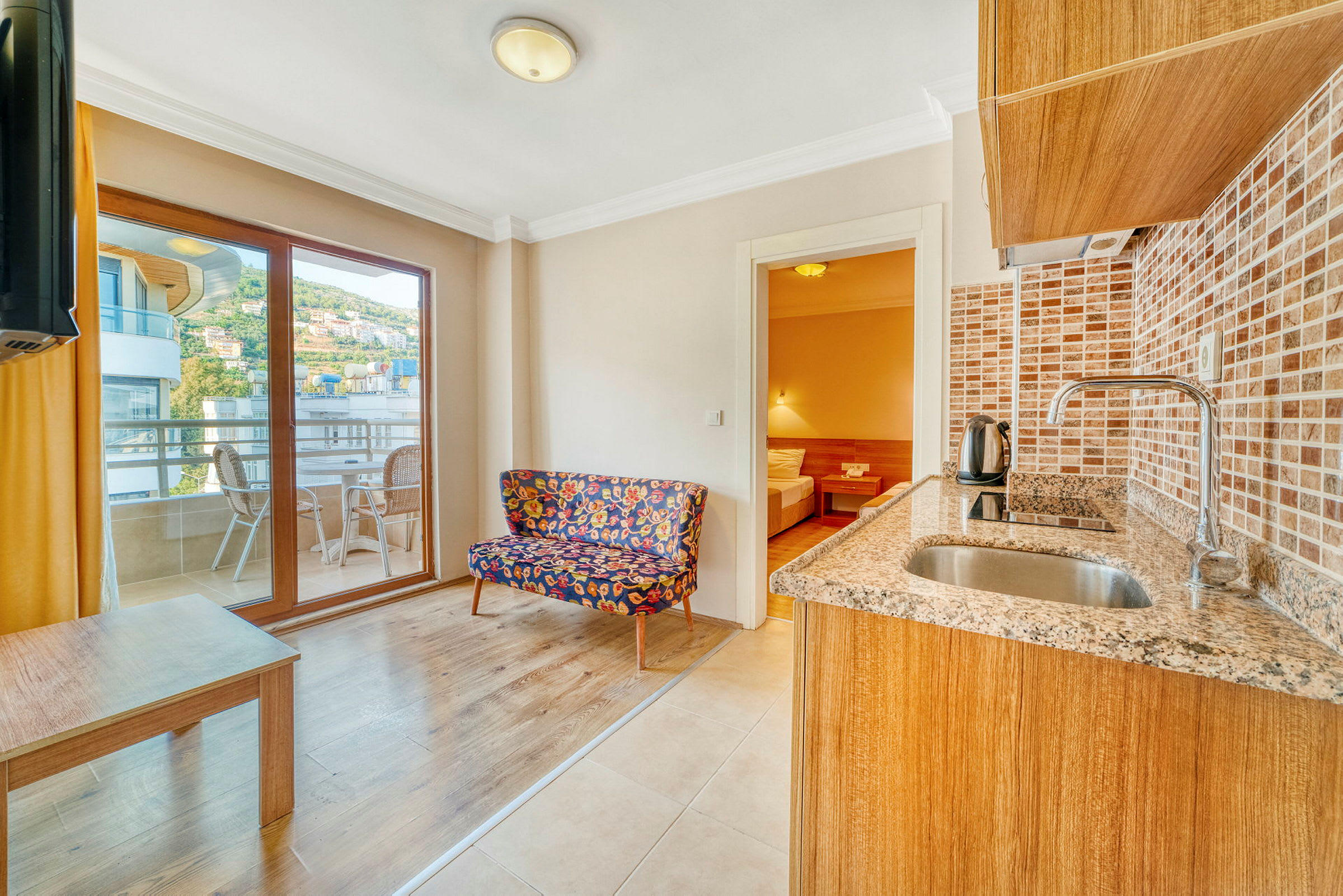 Et rum med køkkenområde, farverig stol og glasdøre til en altan. (AI-genereret tekst)