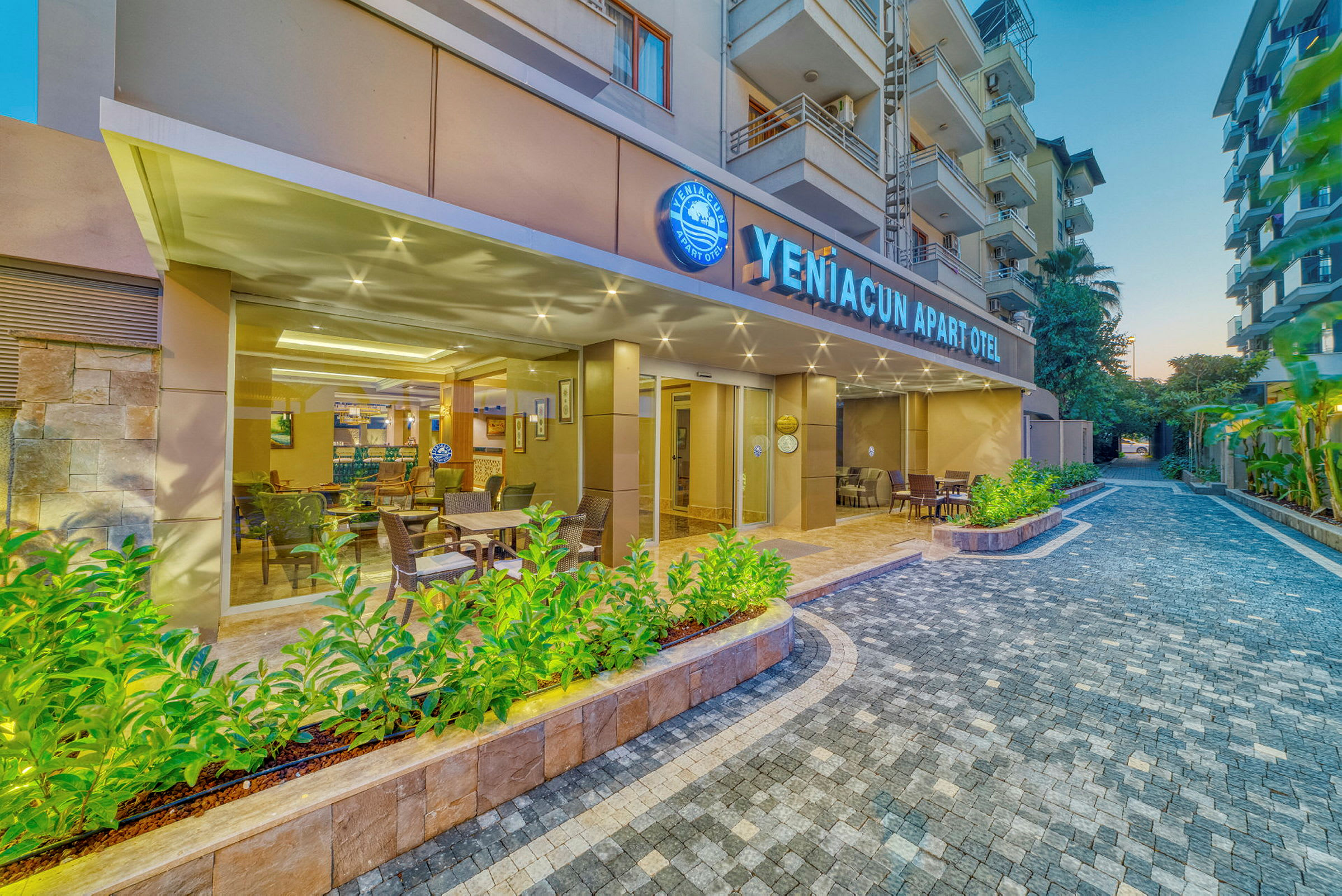 Udendørsområde ved YenĂ?acun Apart Otel med siddepladser og beplantning. (AI-genereret tekst)
