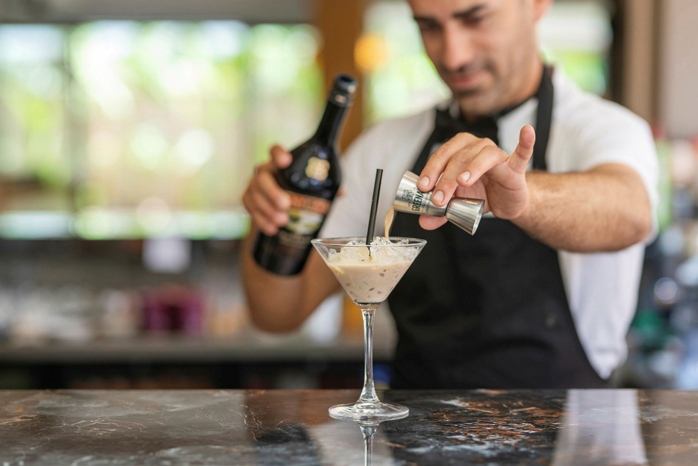 En bartender der forbereder en cocktail med flødelikør. (AI-genereret tekst)
