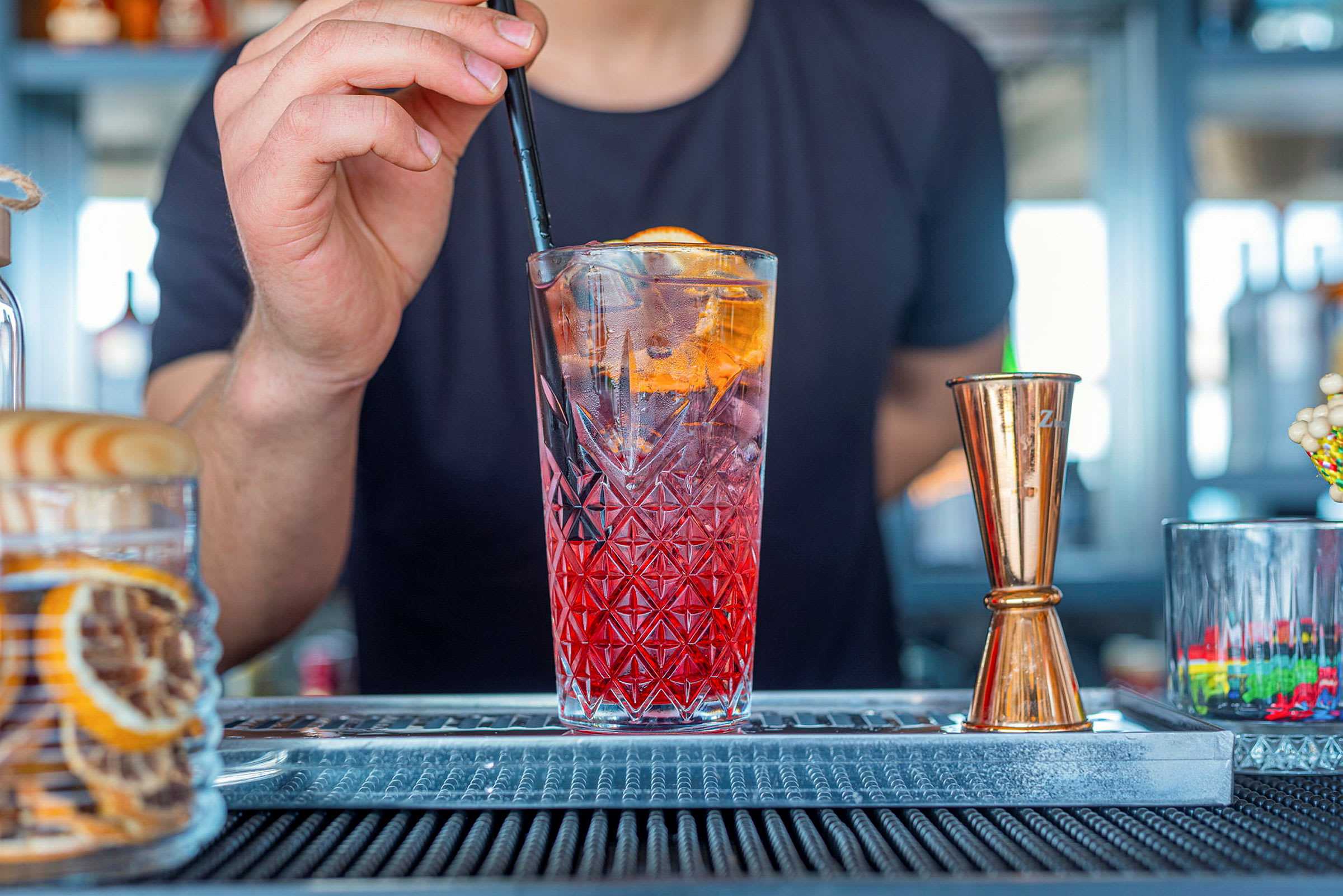En drink med is og et sugerør holdes ved en bar. (AI-genereret tekst)