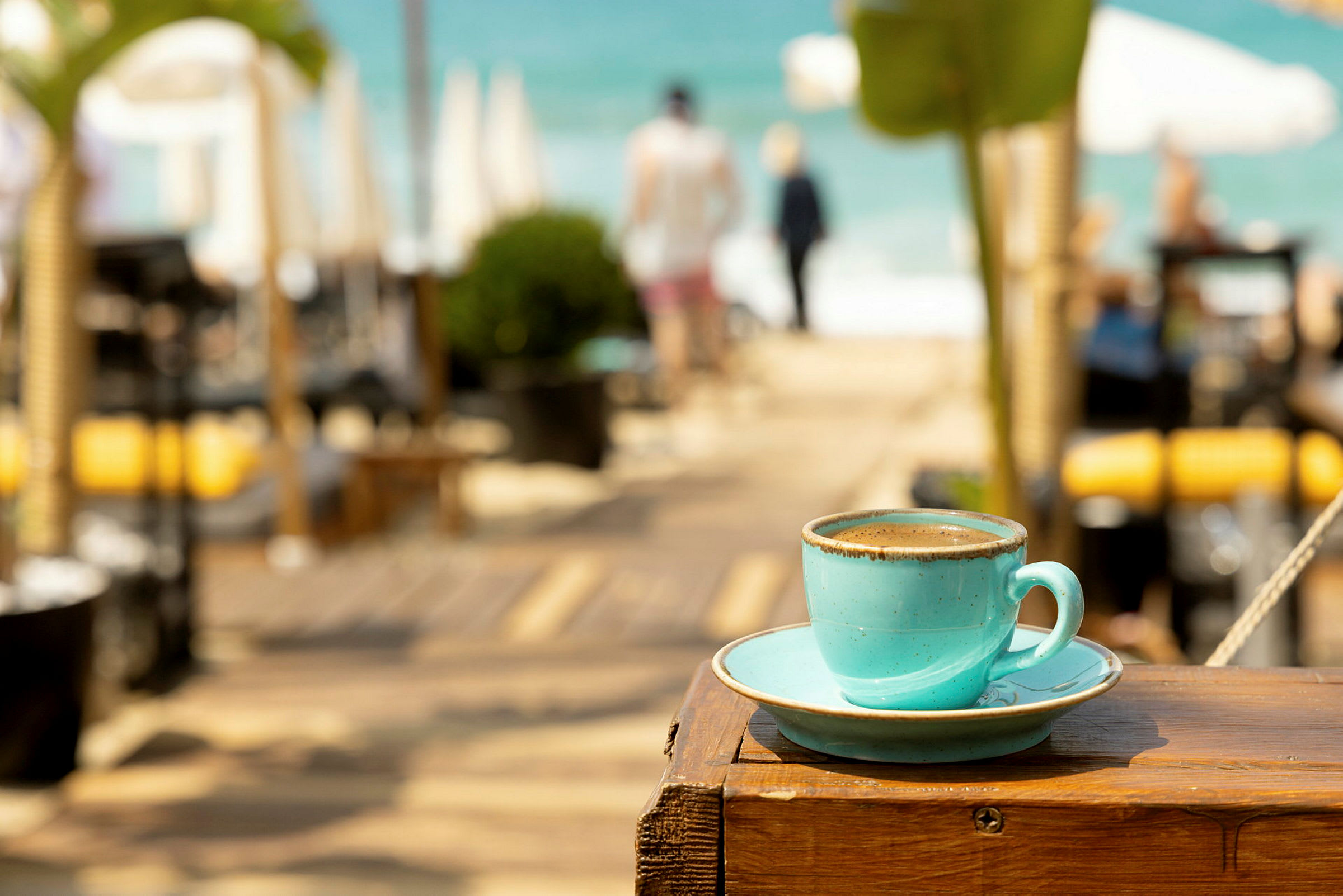 En kop kaffe på en træoverflade med en strand i baggrunden. (AI-genereret tekst)
