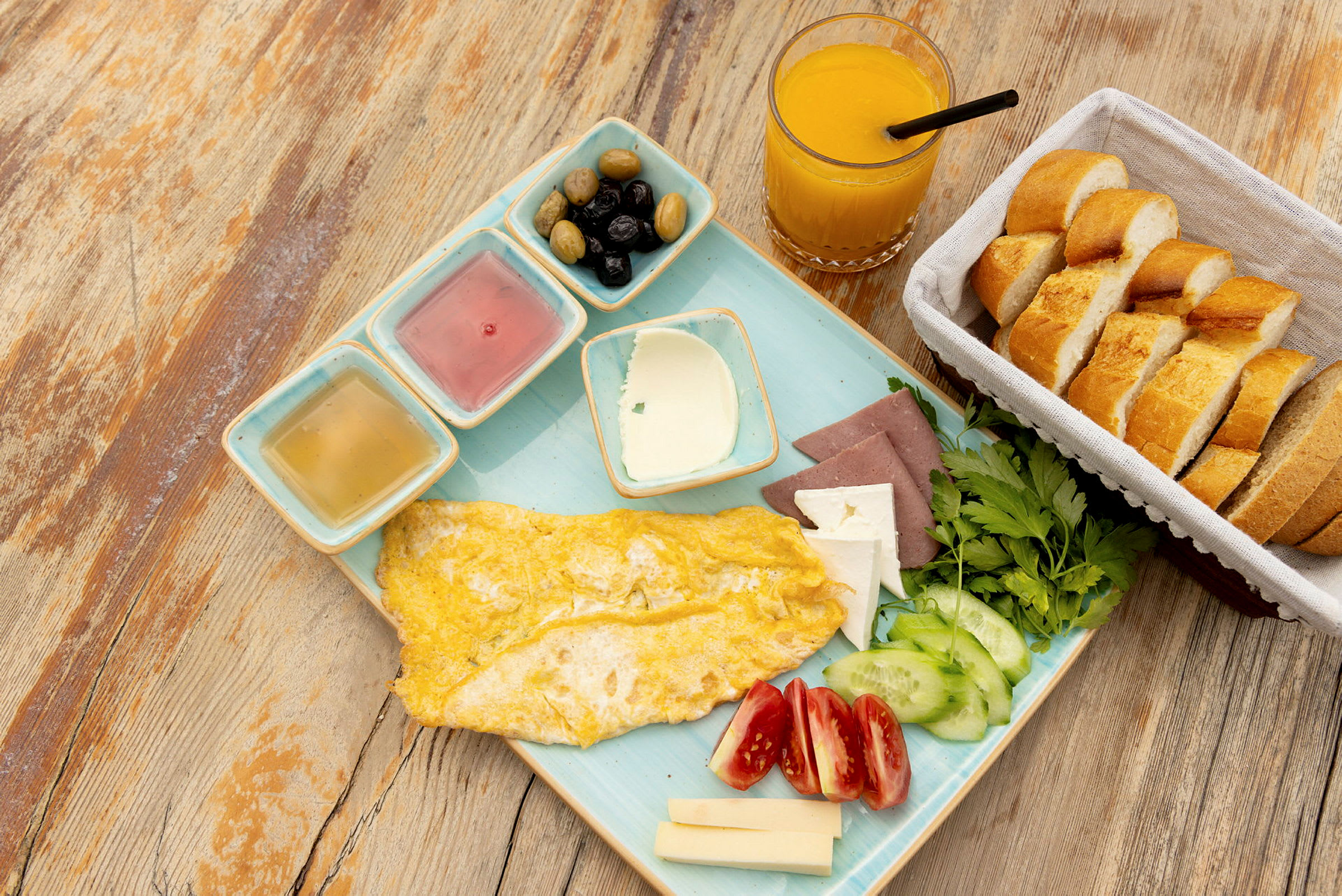 En morgenmad med omelet, grøntsager, ost, brød, oliven og appelsinjuice. (AI-genereret tekst)
