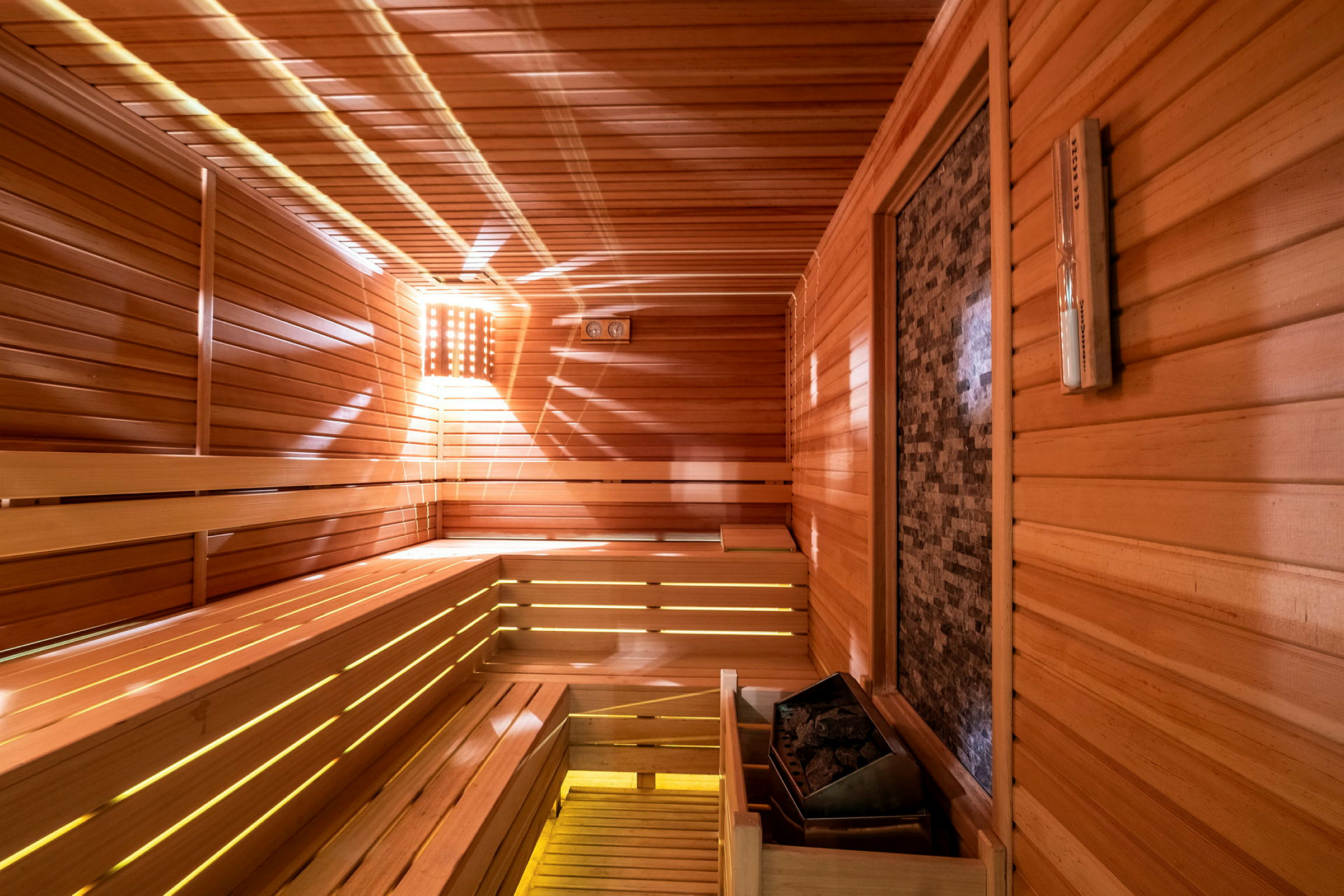 En sauna med træpaneler og en saunaovn ses. (AI-genereret tekst)