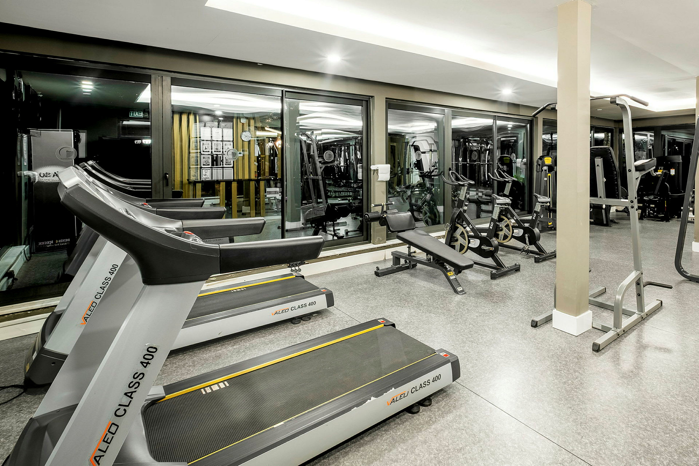 Et fitnesscenter med løbebånd, motionscykler og styrketræningsudstyr. (AI-genereret tekst)
