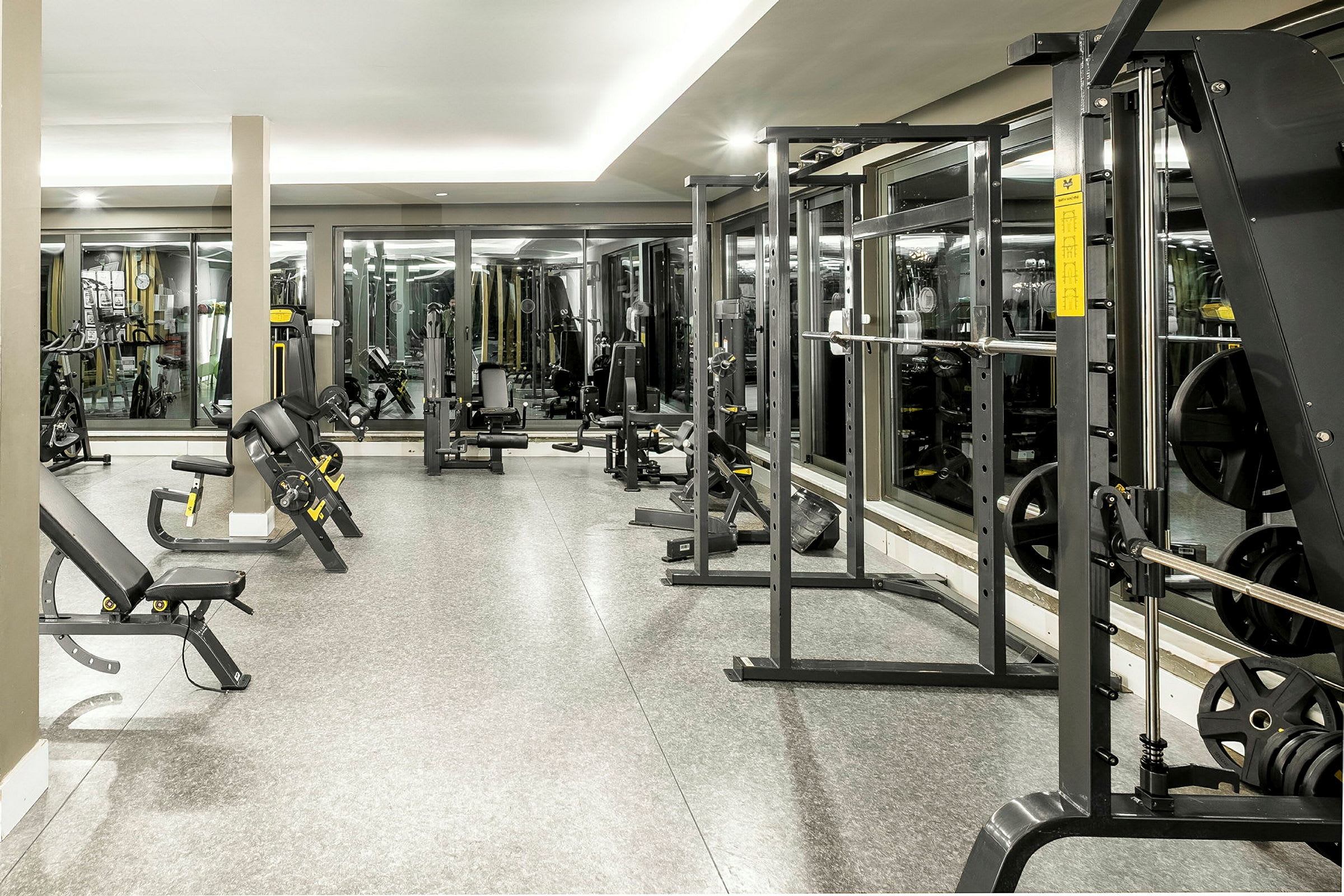 Et veludstyret fitnesscenter med forskellige træningsmaskiner og spejle langs væggene. (AI-genereret tekst)