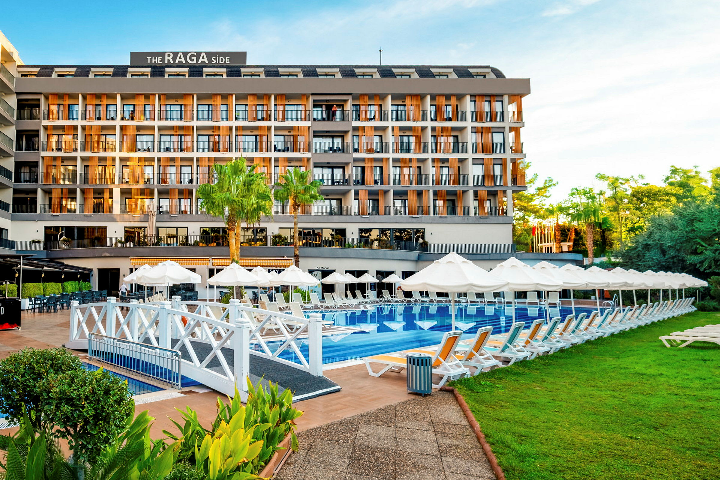 Et hotel med en pool foran, omgivet af liggestole og grønne områder. (AI-genereret tekst)