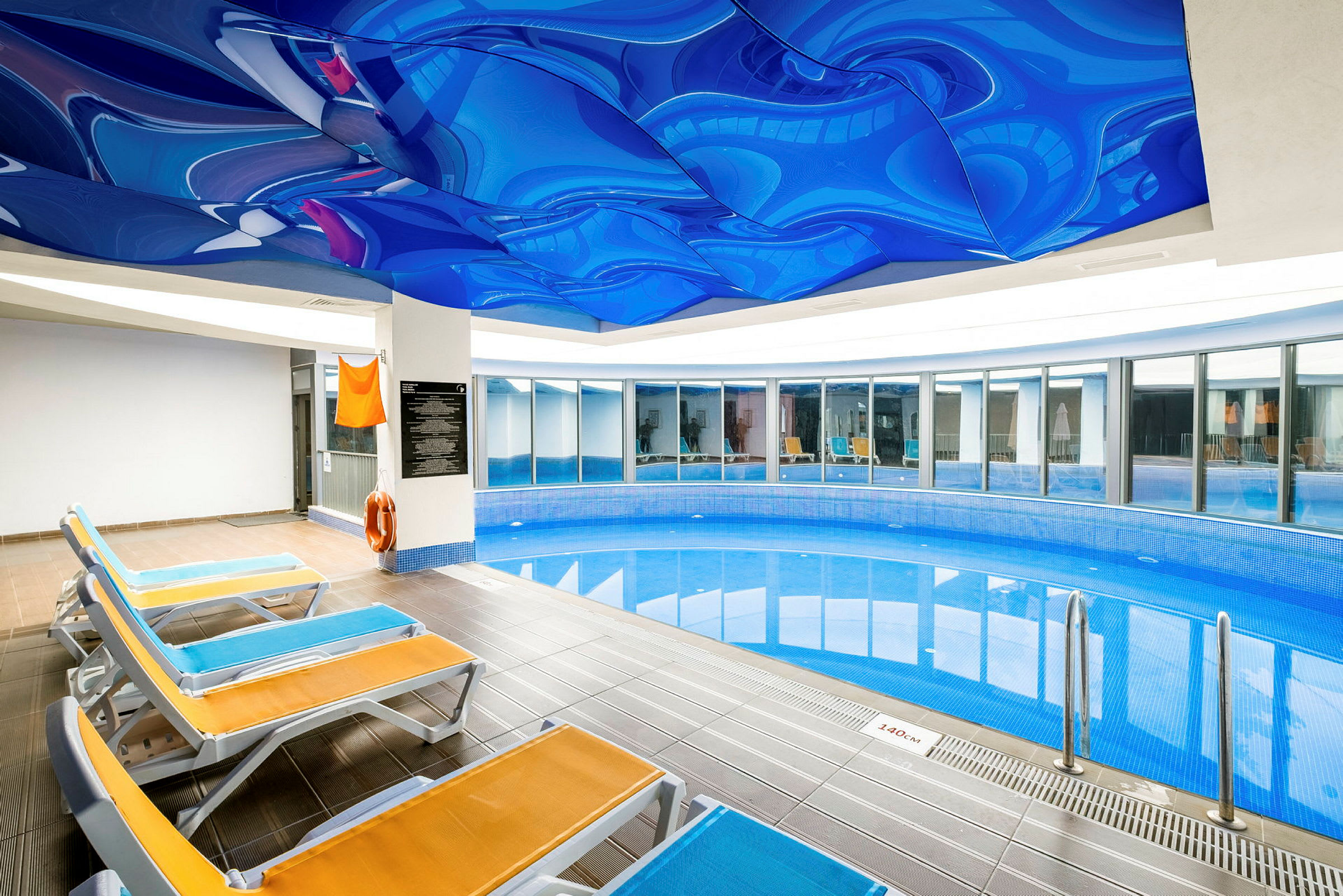 Indendørs pool med liggestole og udsmykket loft. (AI-genereret tekst)