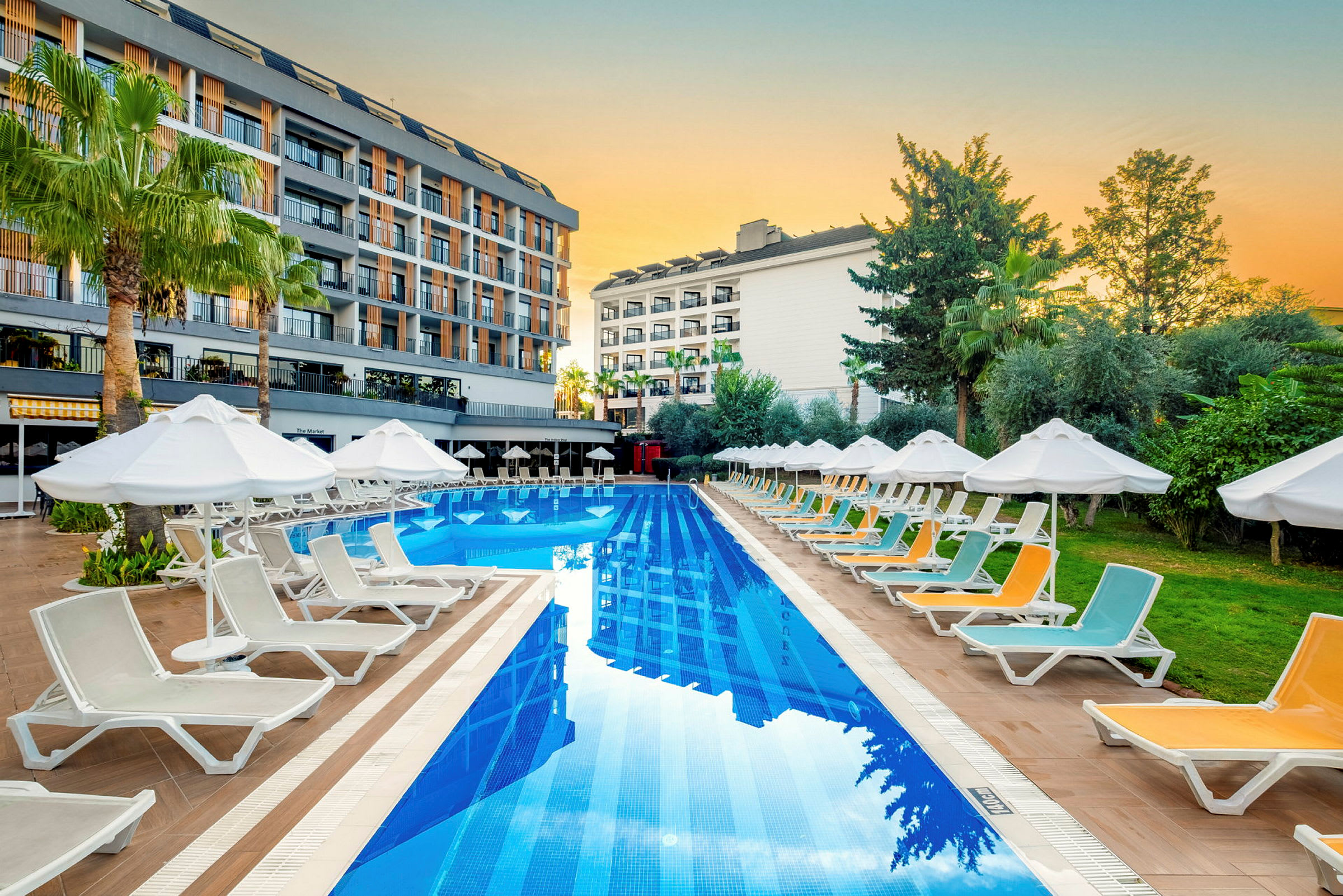 En pool ved et hotelområde omgivet af liggestole og parasoller. (AI-genereret tekst)