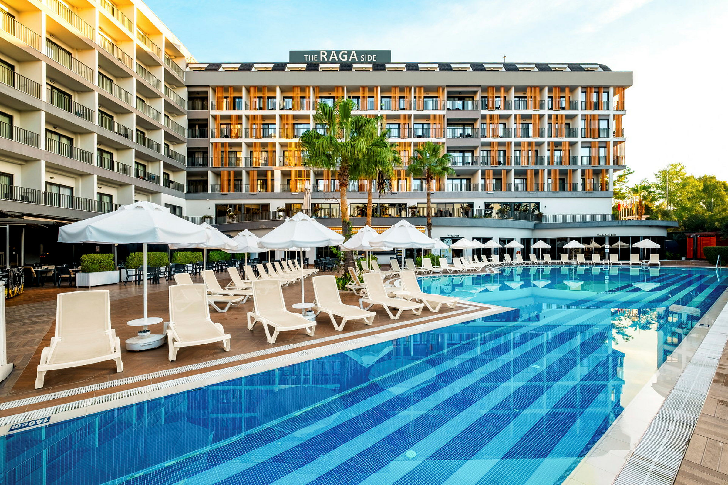 Et hotel ved en pool med liggestole og parasoller. (AI-genereret tekst)