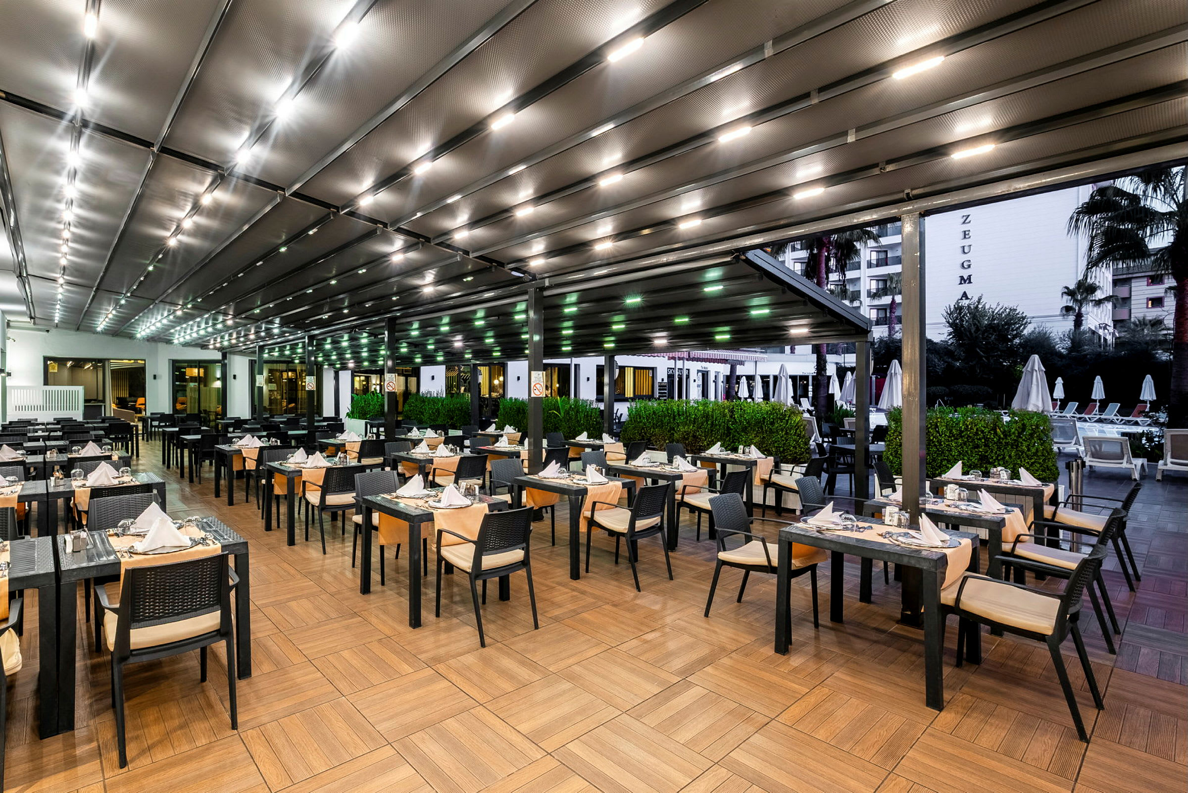 En udendørsrestaurant ved en pool, med opstillede borde og stole. (AI-genereret tekst)