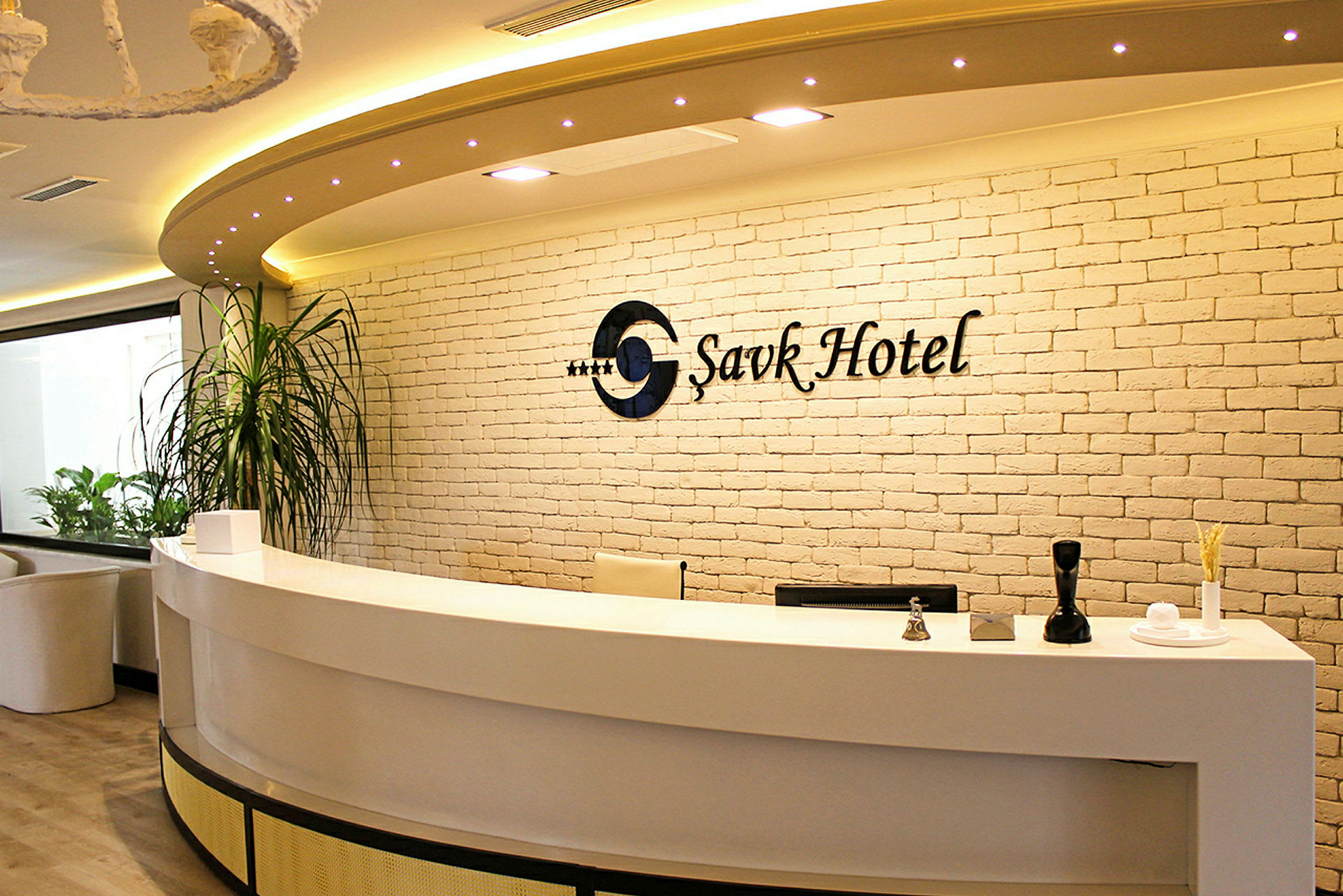 Receptionen på et hotel med en hvid skranke og murstensvæg. (AI-genereret tekst)