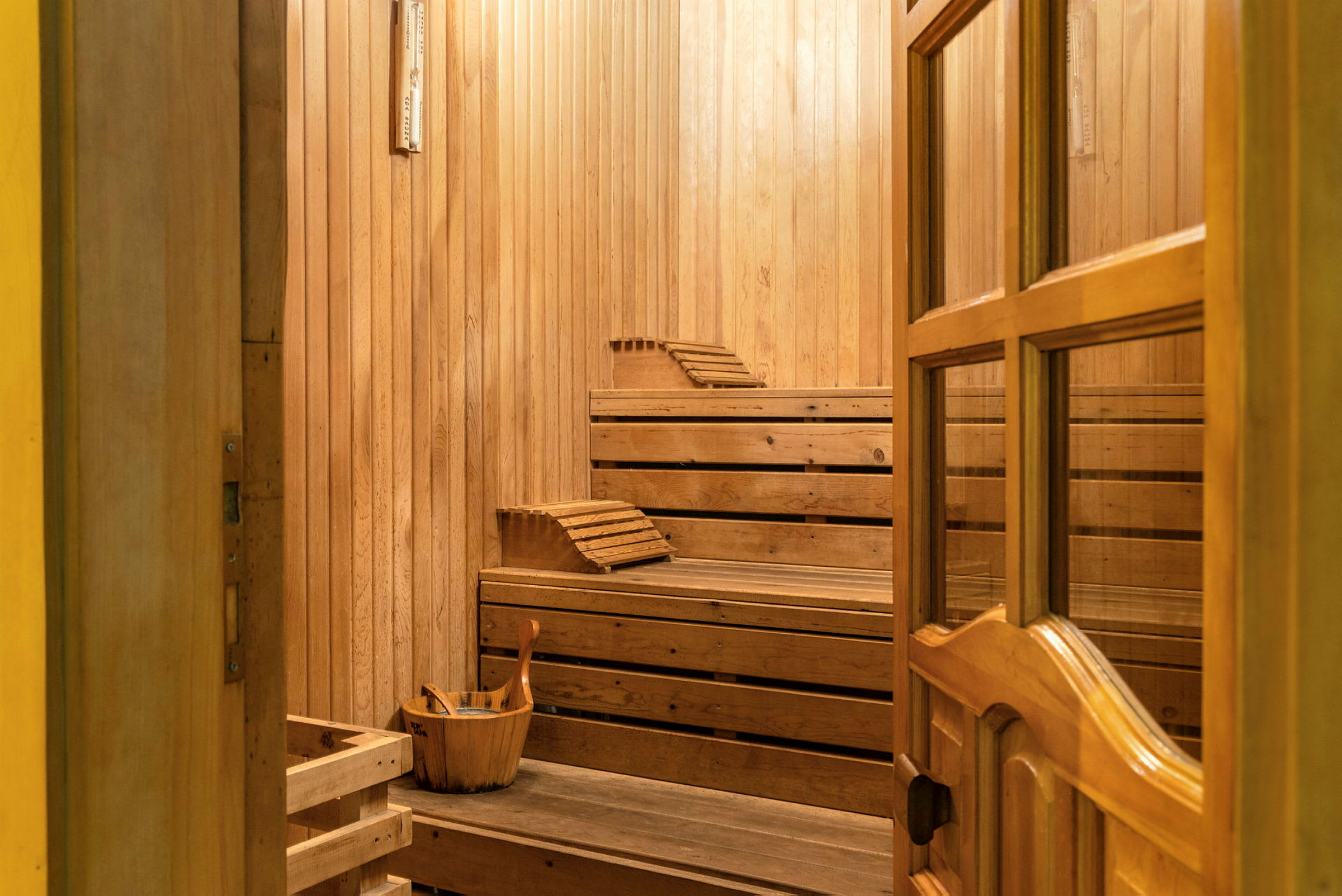 En sauna med træinteriør, bænke og en spand med en øse. (AI-genereret tekst)