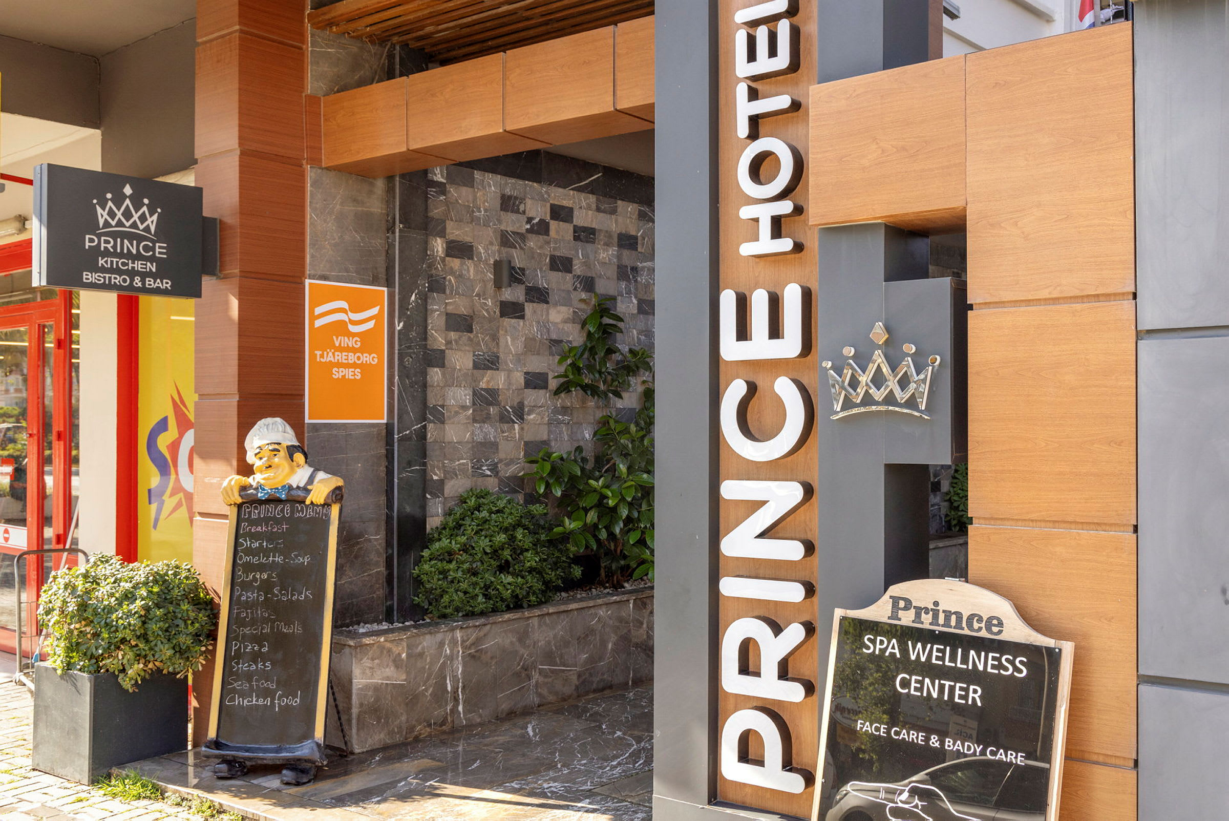 Indgang til Prince Hotel med skilte for restaurant og wellness-center. (AI-genereret tekst)