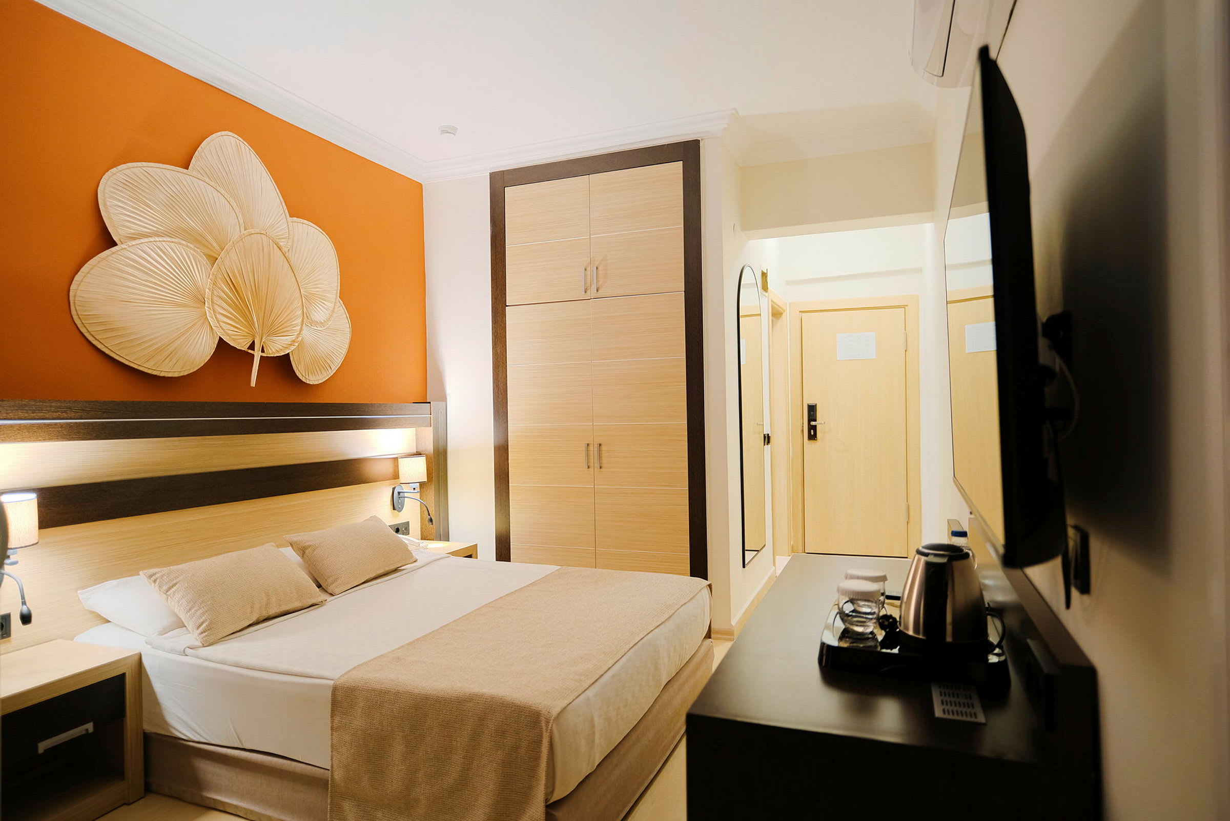 Et hotelværelse med en seng, garderobe og orange vægdekoration. (AI-genereret tekst)