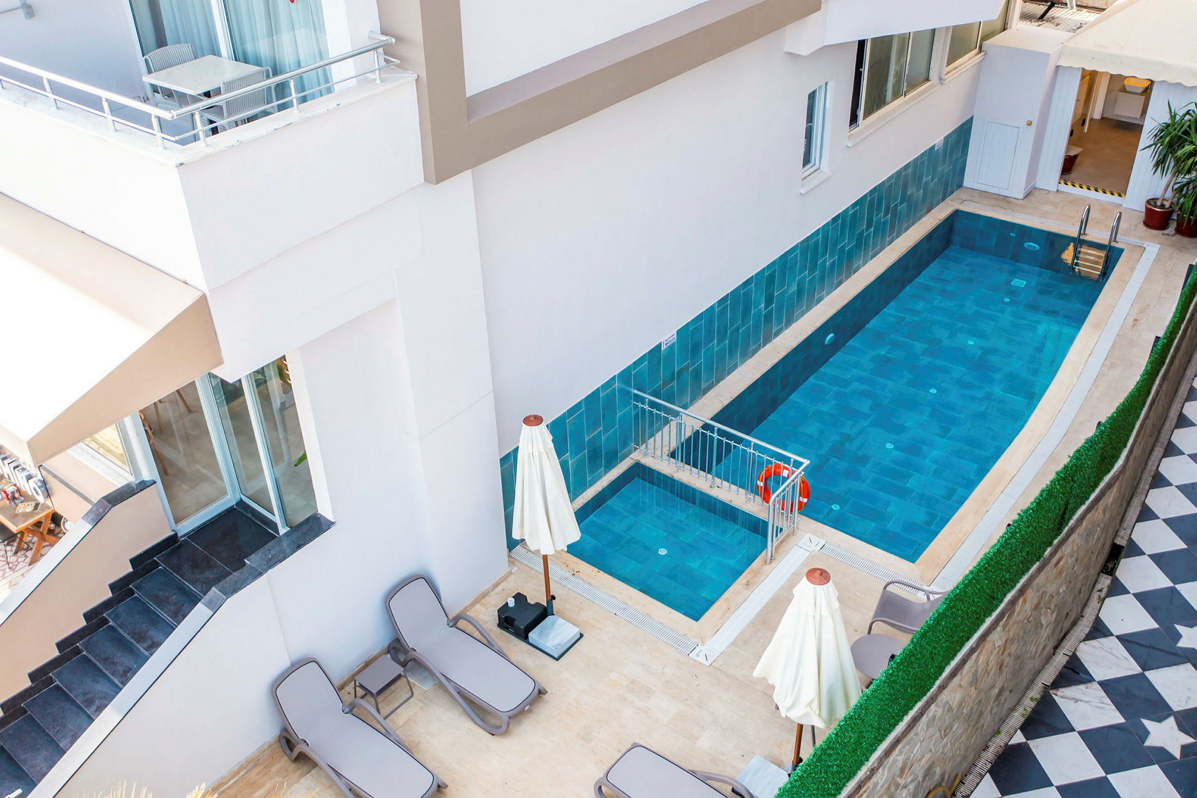 En lille pool ved et hotel med liggestole og parasoller omkring. (AI-genereret tekst)