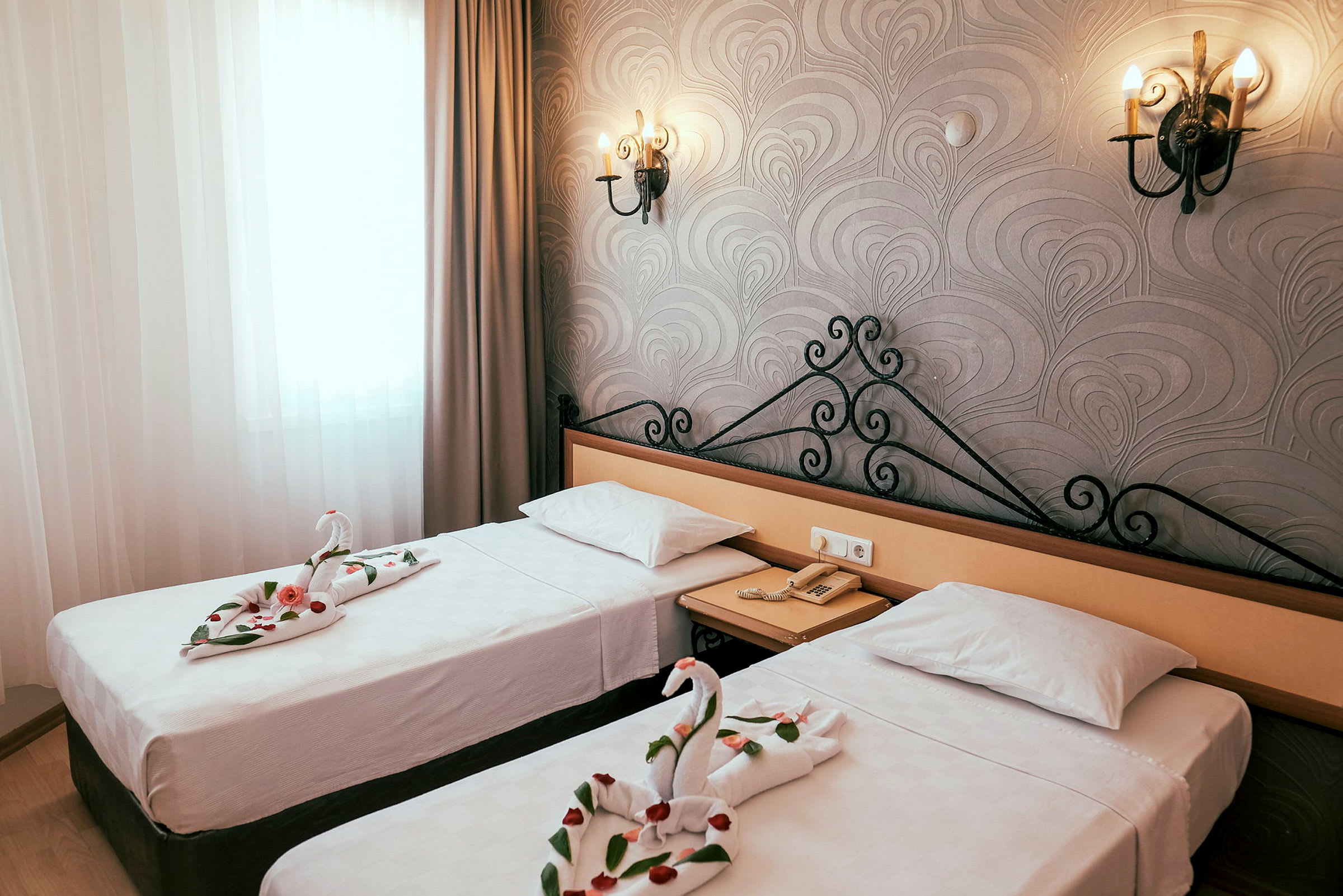Billede af et hotelværelse med to enkeltsenge. Håndklæder på sengene er foldet som svaner med dekorative rosenblade. (AI-genereret tekst)