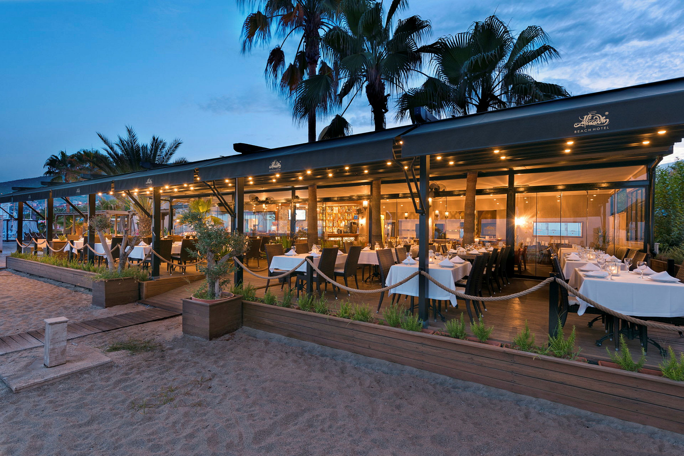 En restaurant ved stranden med hvide duge om aftenen. (AI-genereret tekst)