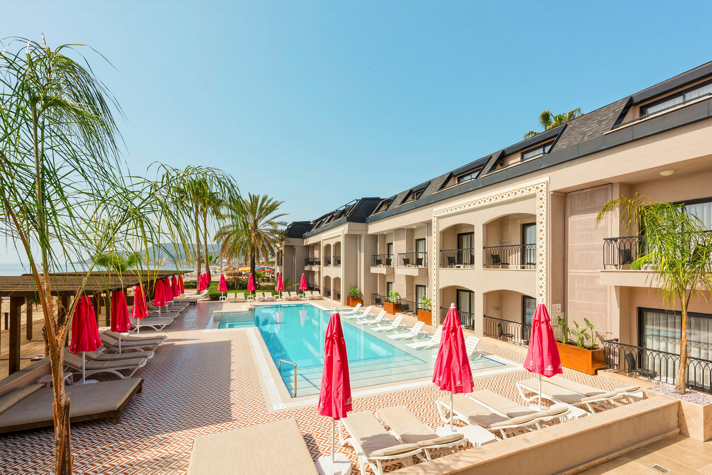 Poolområde med solsenge og parasoller ved hotelbygning. (AI-genereret tekst)