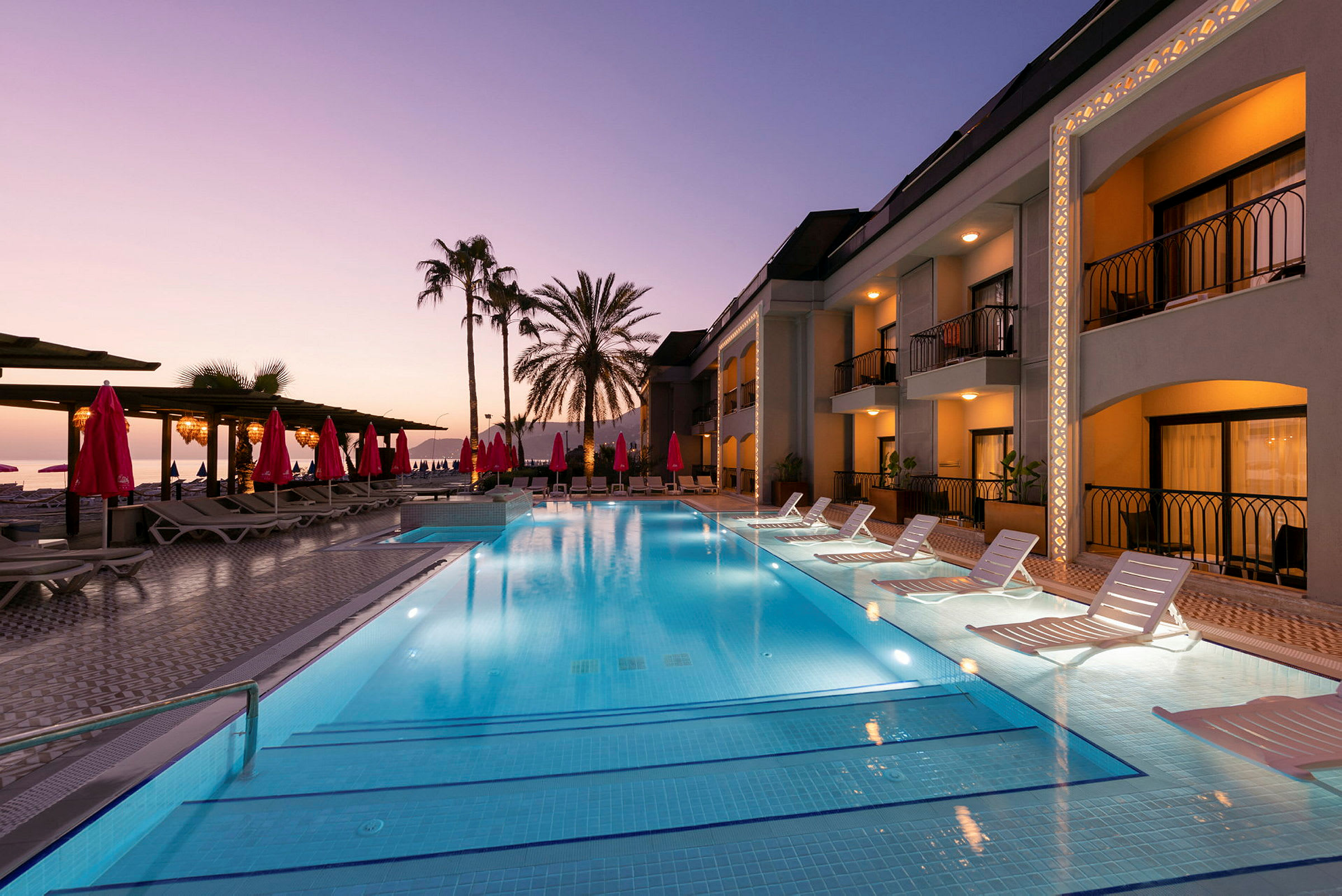 Udendørs pool ved et hotel med solnedgang i baggrunden. (AI-genereret tekst)