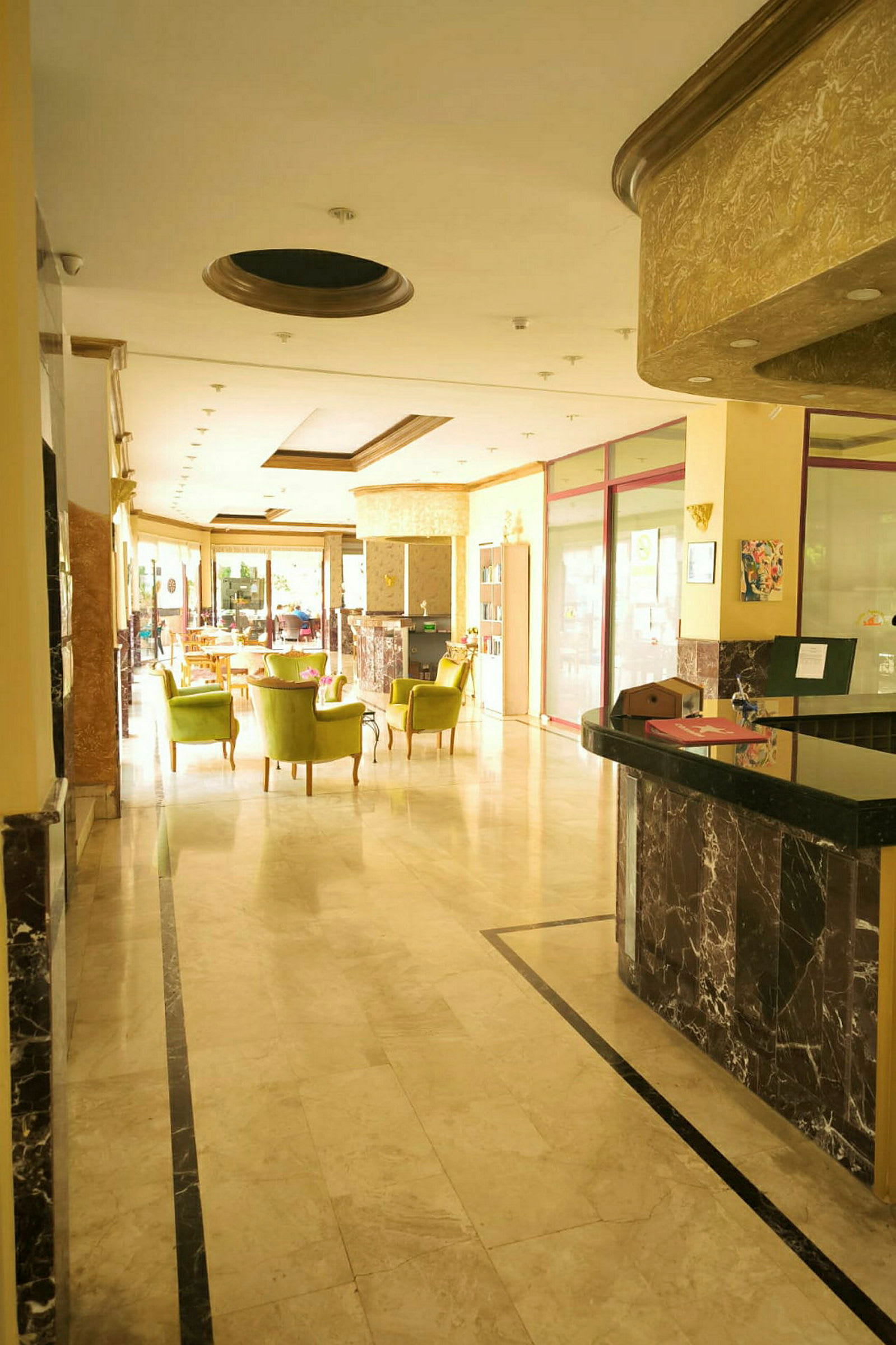 Hotellets reception med marmorgulv og grønpolstrede stole. (AI-genereret tekst)