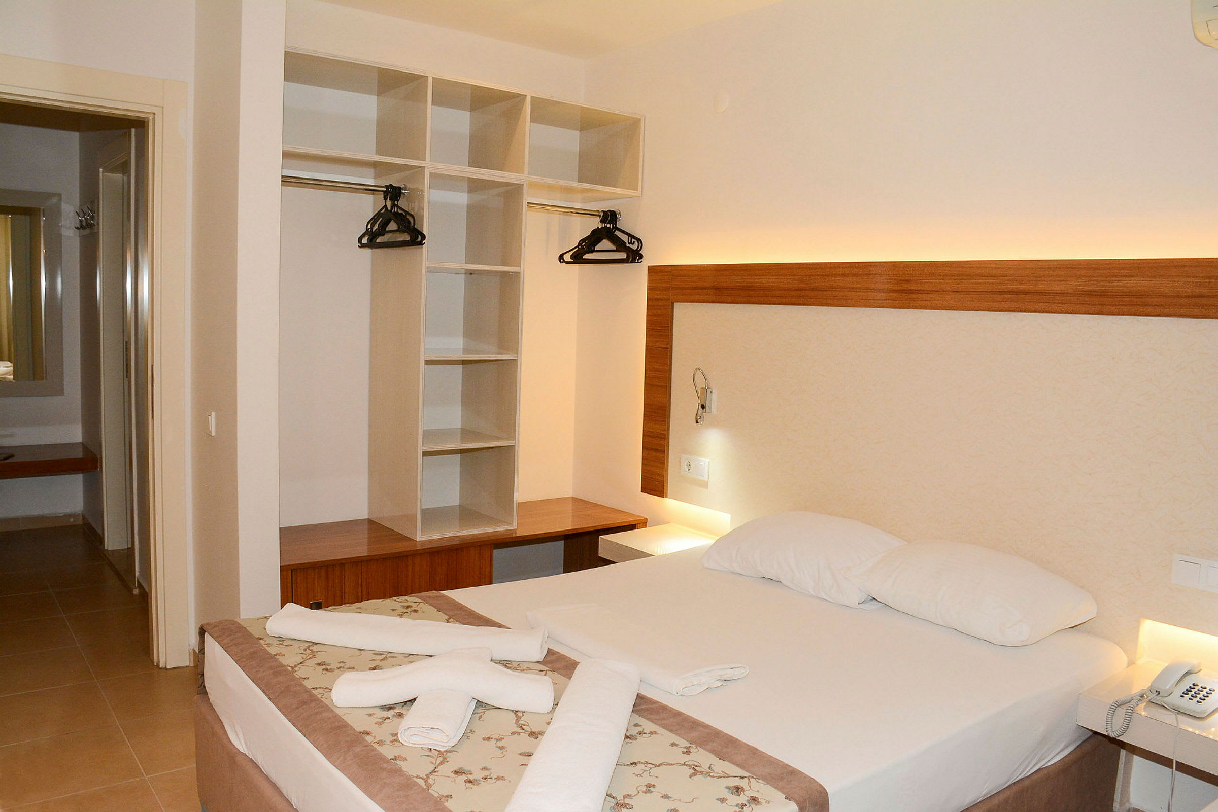 Hotelværelse med dobbeltseng, garderobe og natbord. (AI-genereret tekst)