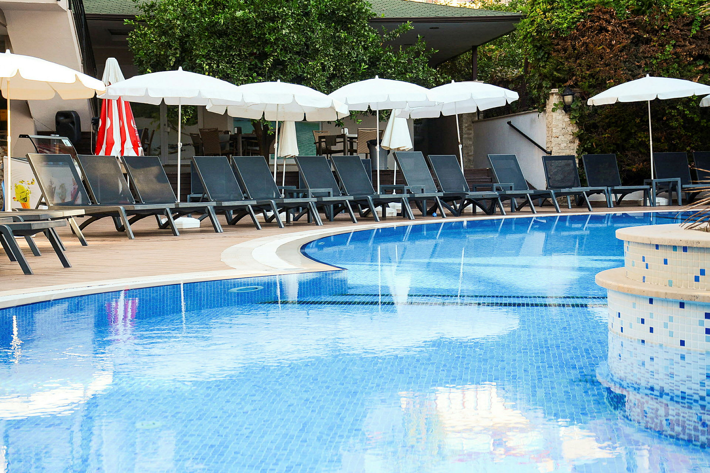 Pool med liggestole og parasoller i baggrunden. (AI-genereret tekst)