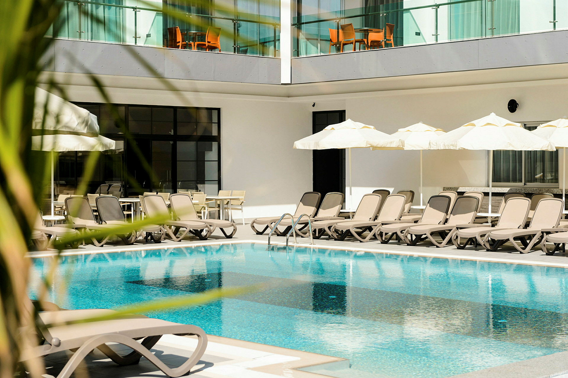 Udendørs pool med liggestole og parasoller ved hotel. (AI-genereret tekst)