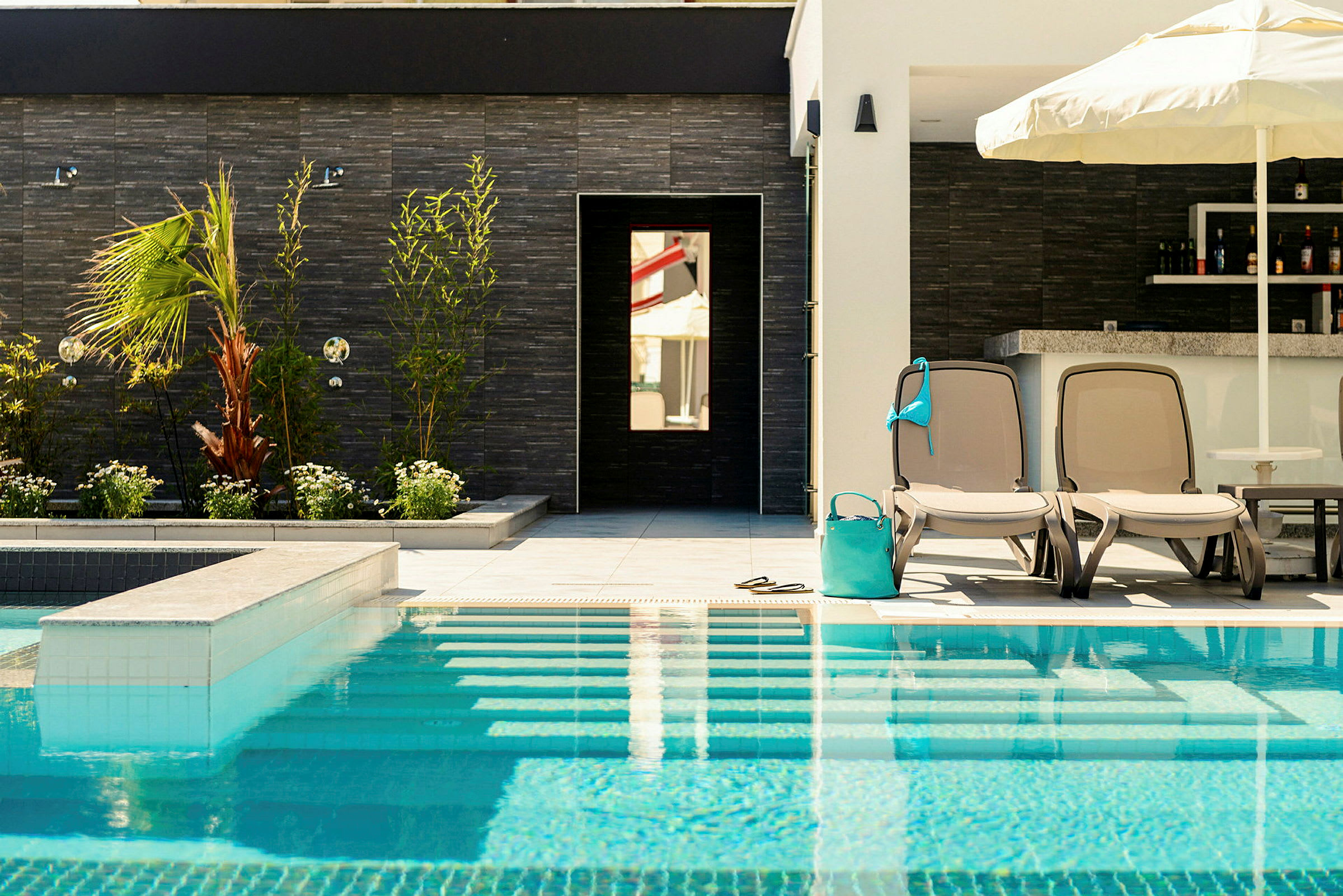 To solsenge og parasol ved en pool. (AI-genereret tekst)