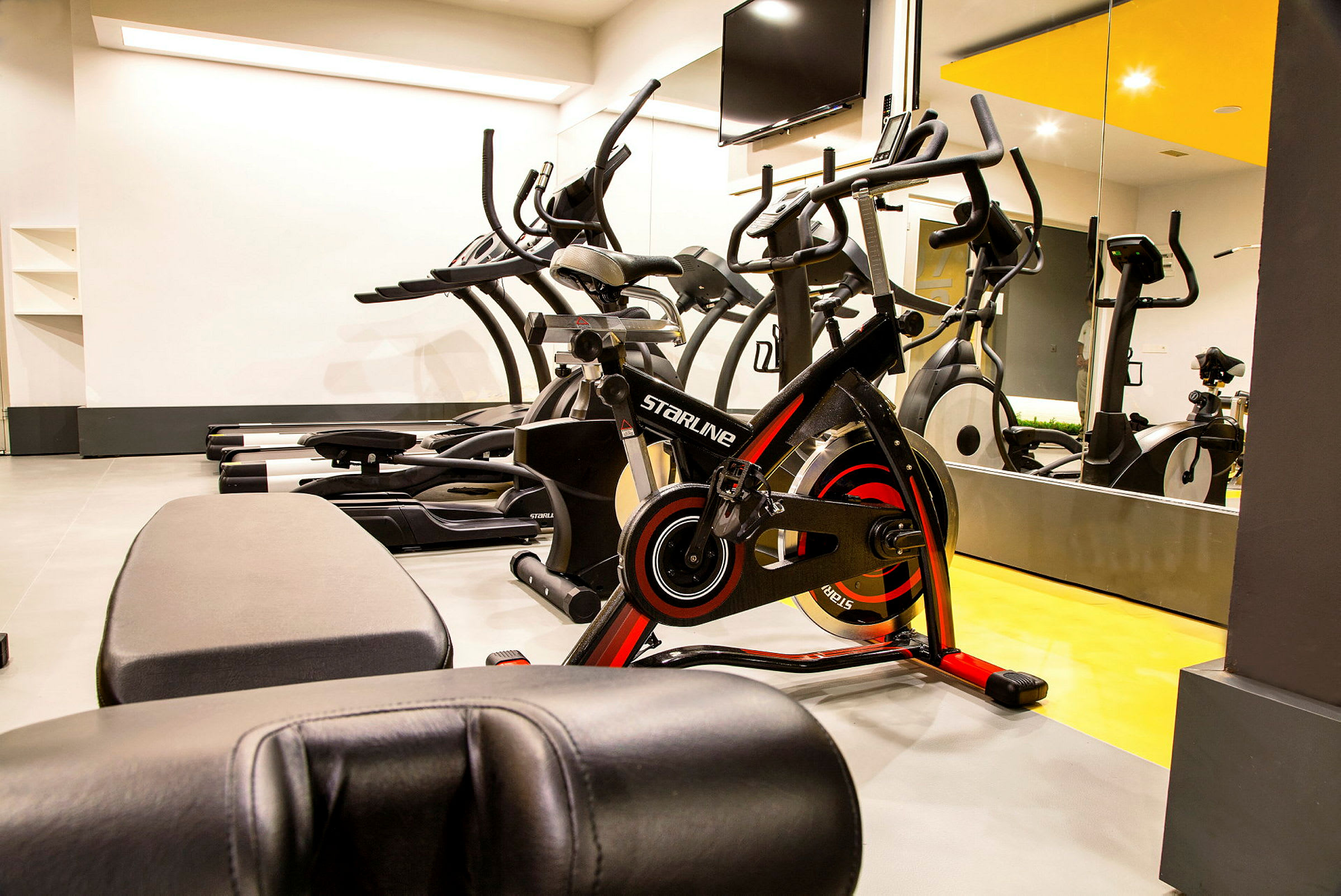 Et fitnessrum med træningsmaskiner og spejle på væggen. (AI-genereret tekst)