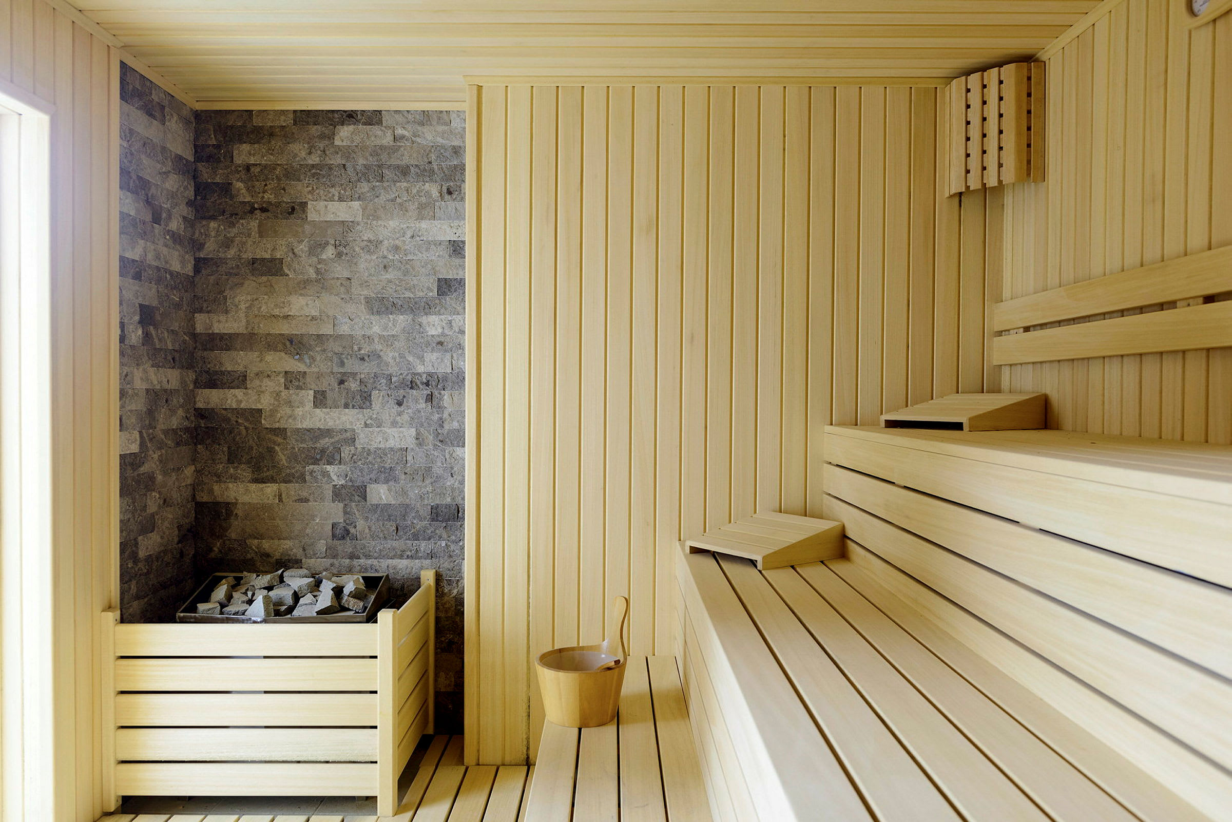 Inde i en sauna med træpaneler og sten på varmekilden. (AI-genereret tekst)