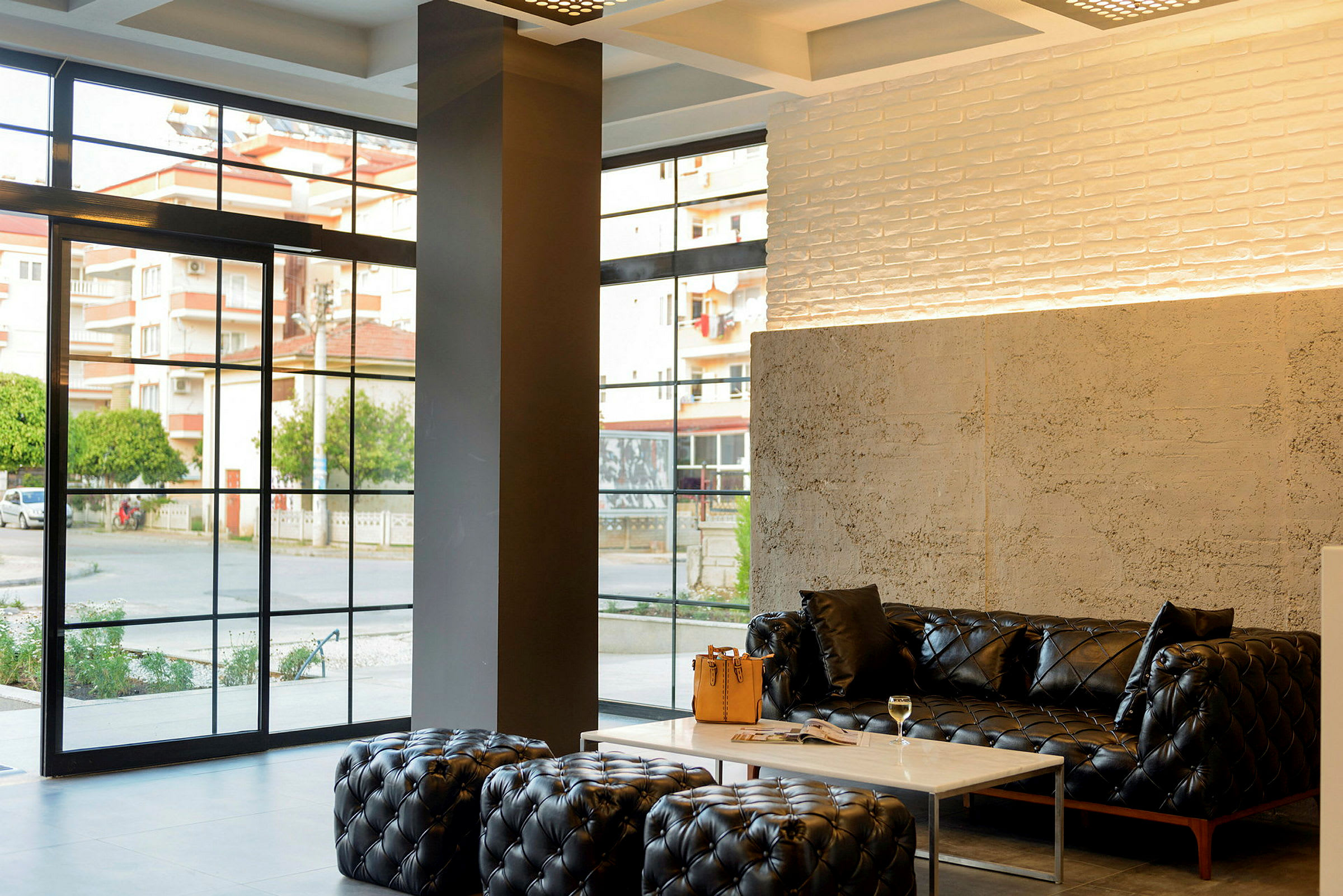 Moderne lobby med sorte sofaer, et marmorbord og store vinduer. (AI-genereret tekst)