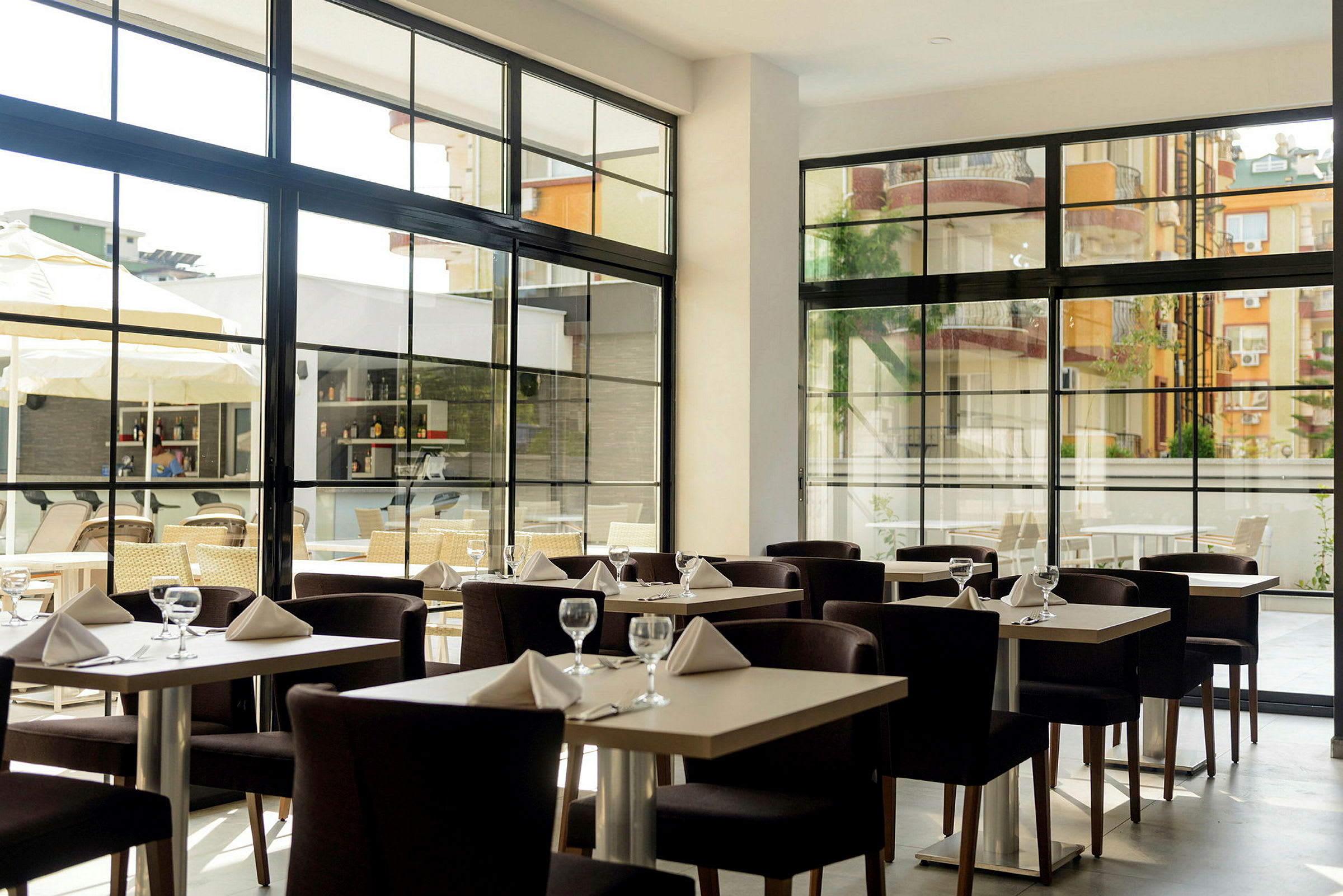 Restaurant med dækkede borde og store vinduer. (AI-genereret tekst)