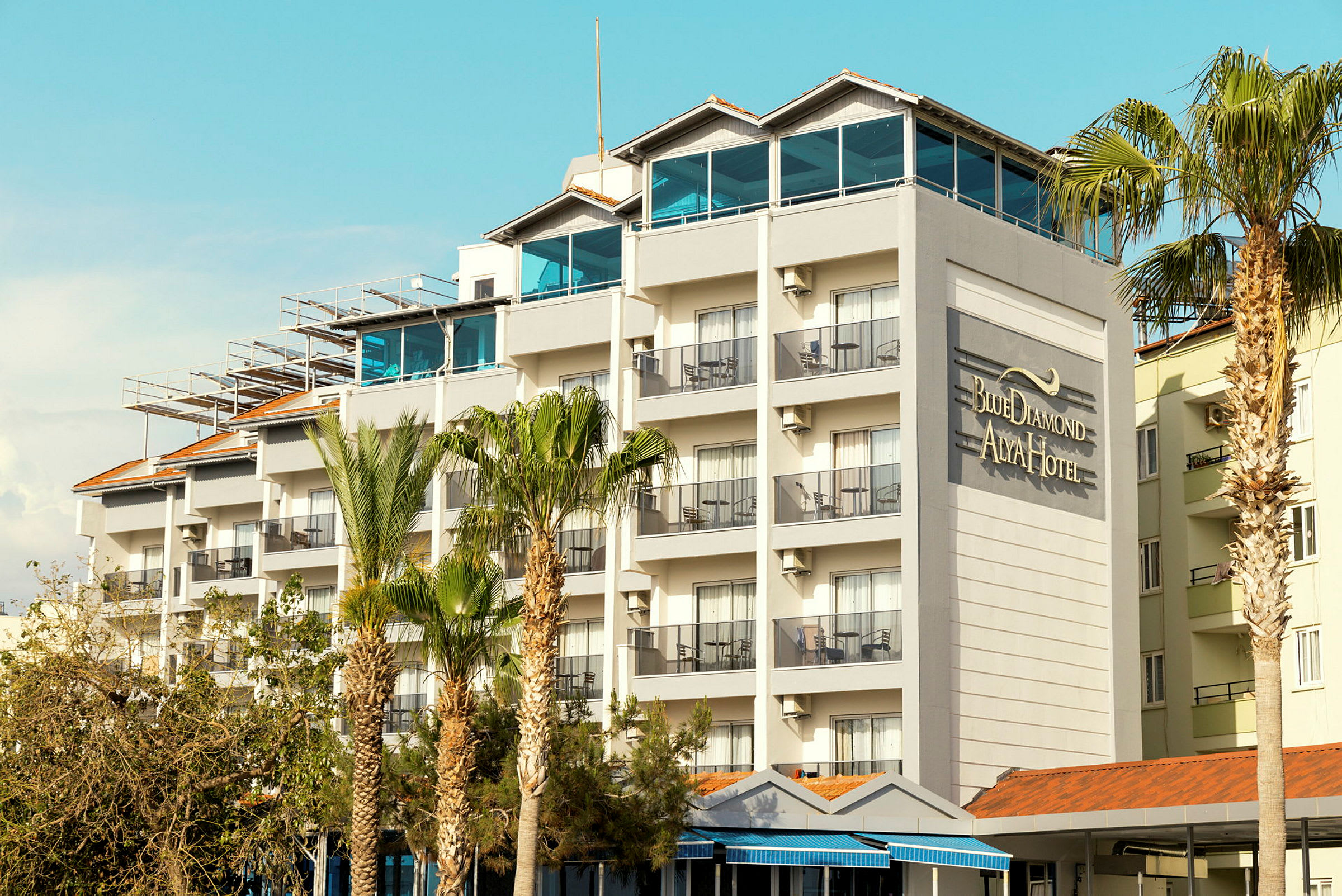 En hotelbygning med flere etager og altaner samt teksten "Blue Diamond Alya Hotel" på væggen. (AI-genereret tekst)